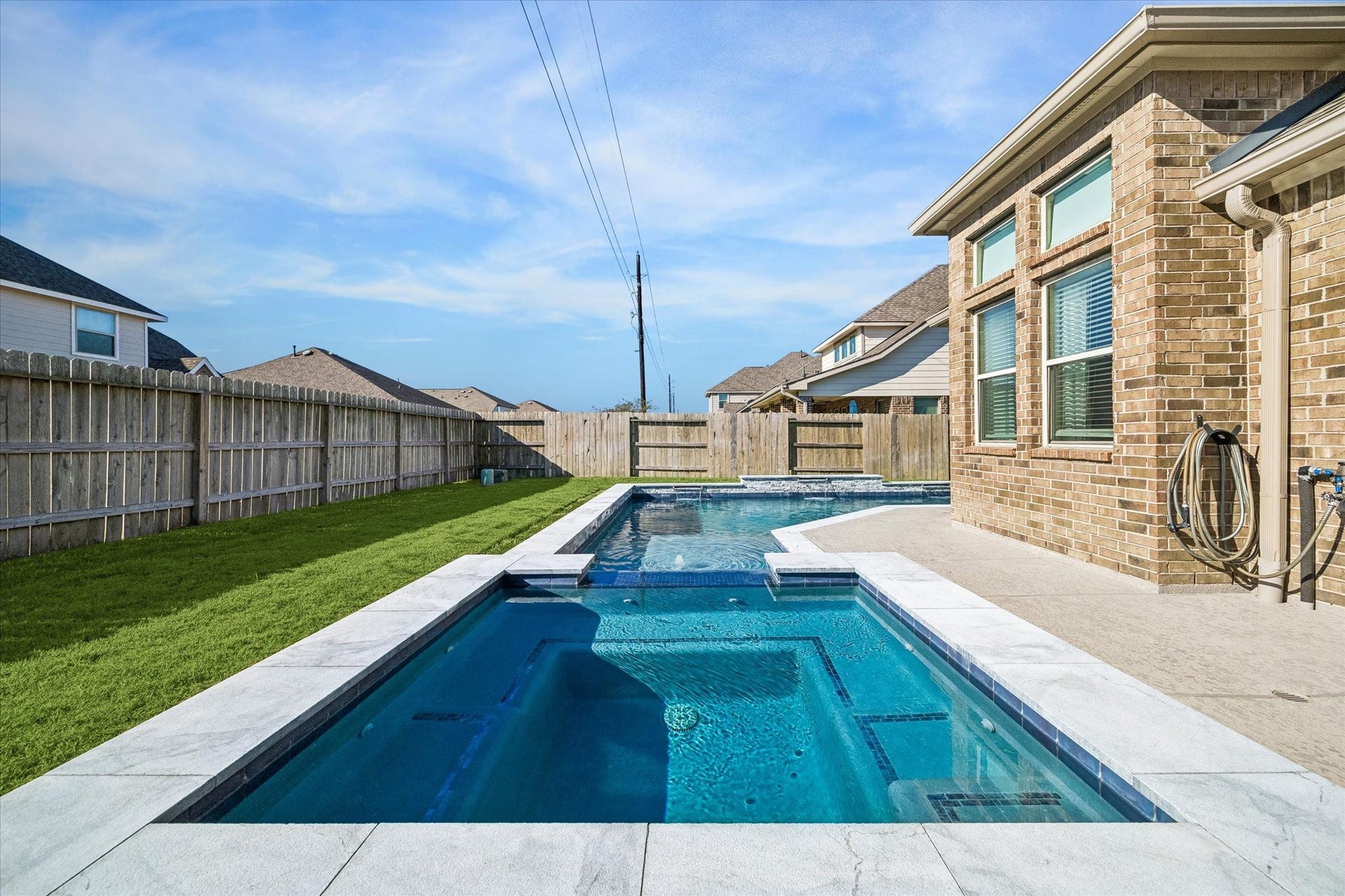 14918 Lake Shore Avenue, Mont Belvieu, TX 77523 Stacked-stone accents and sheer-descent water features bring a custom touch to the pool, while the nearby covered patio and open lawn complete this inviting outdoor setting.