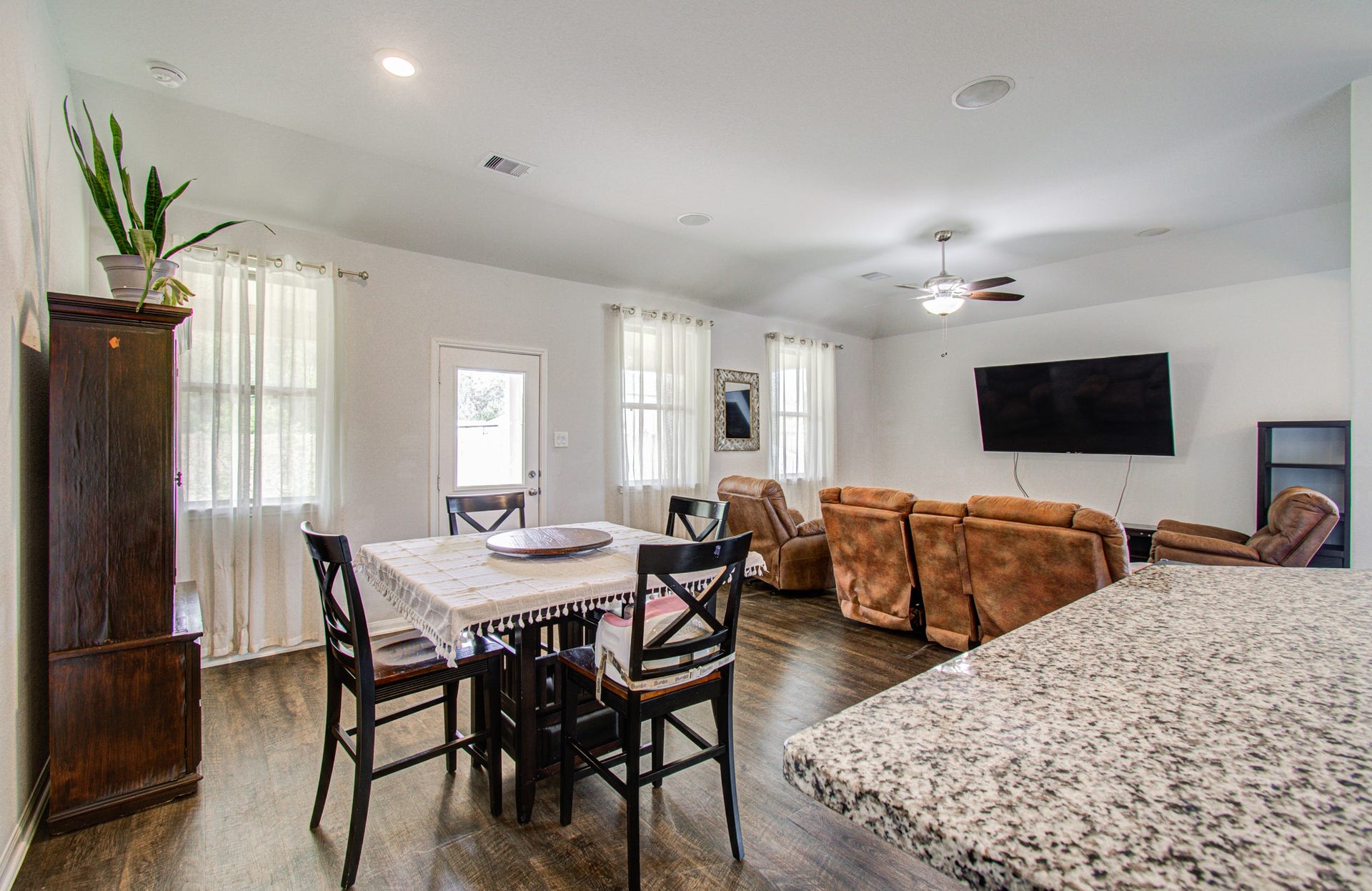 11064 Patriot Court, Cleveland, TX 77328 Bright and spacious open-concept living area featuring a cozy dining space, plush seating, and a wall-mounted TV, complemented by stylish wood flooring and modern finishes.
