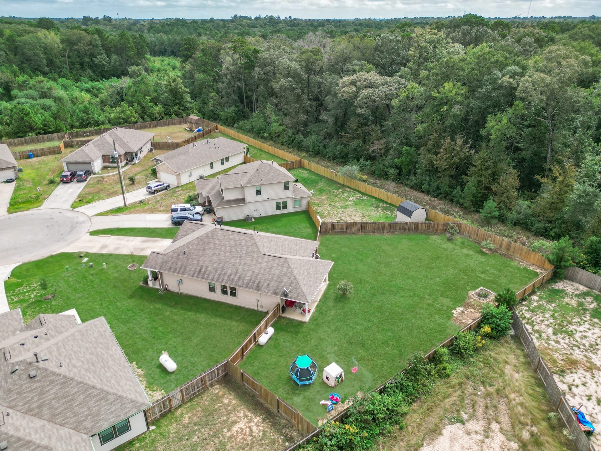 11064 Patriot Court, Cleveland, TX 77328 Spacious backyard with lush greenery and a storage shed, perfect for outdoor activities, all nestled in a tranquil neighborhood setting.