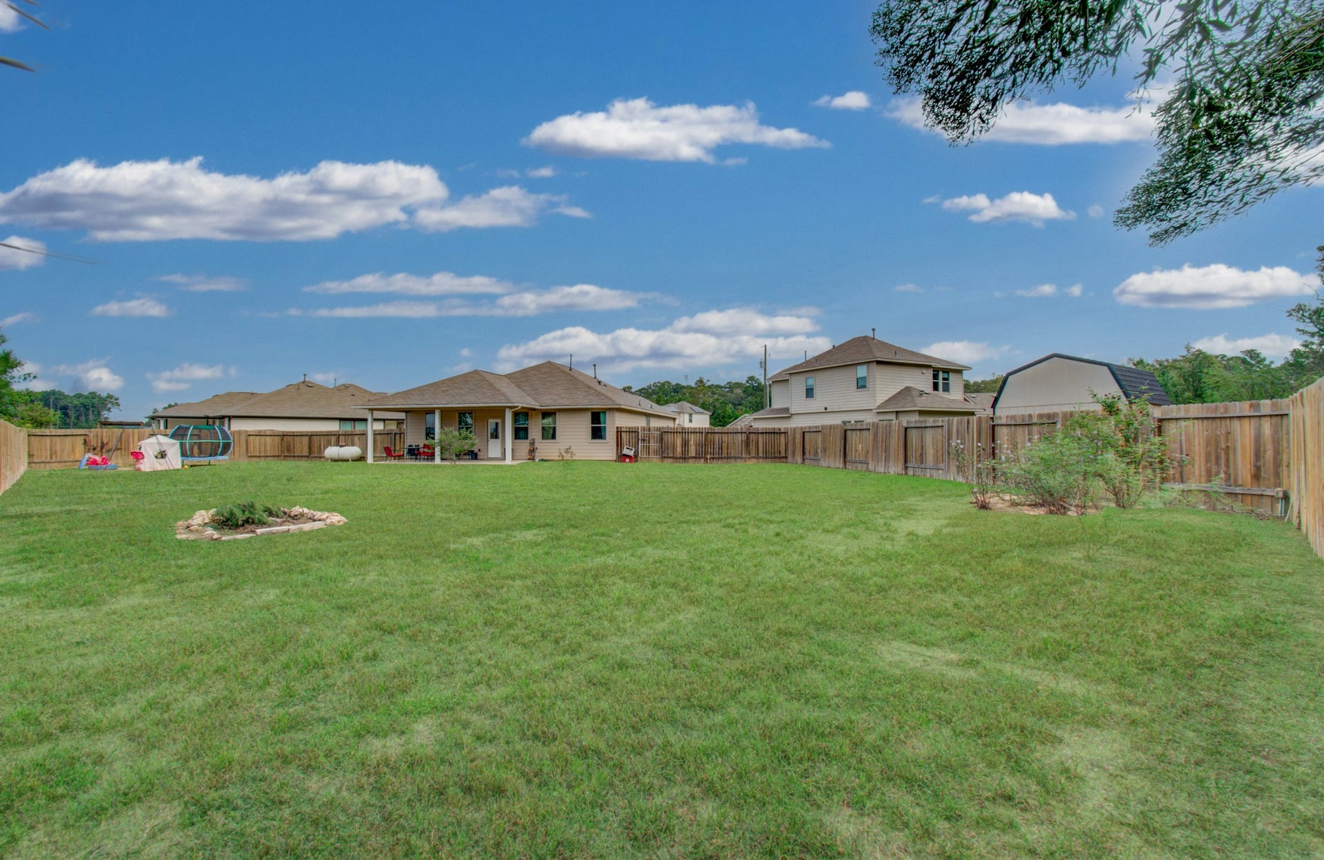 11064 Patriot Court, Cleveland, TX 77328 Spacious backyard with lush green lawn, ideal for outdoor activities, surrounded by a wooden fence for privacy.
