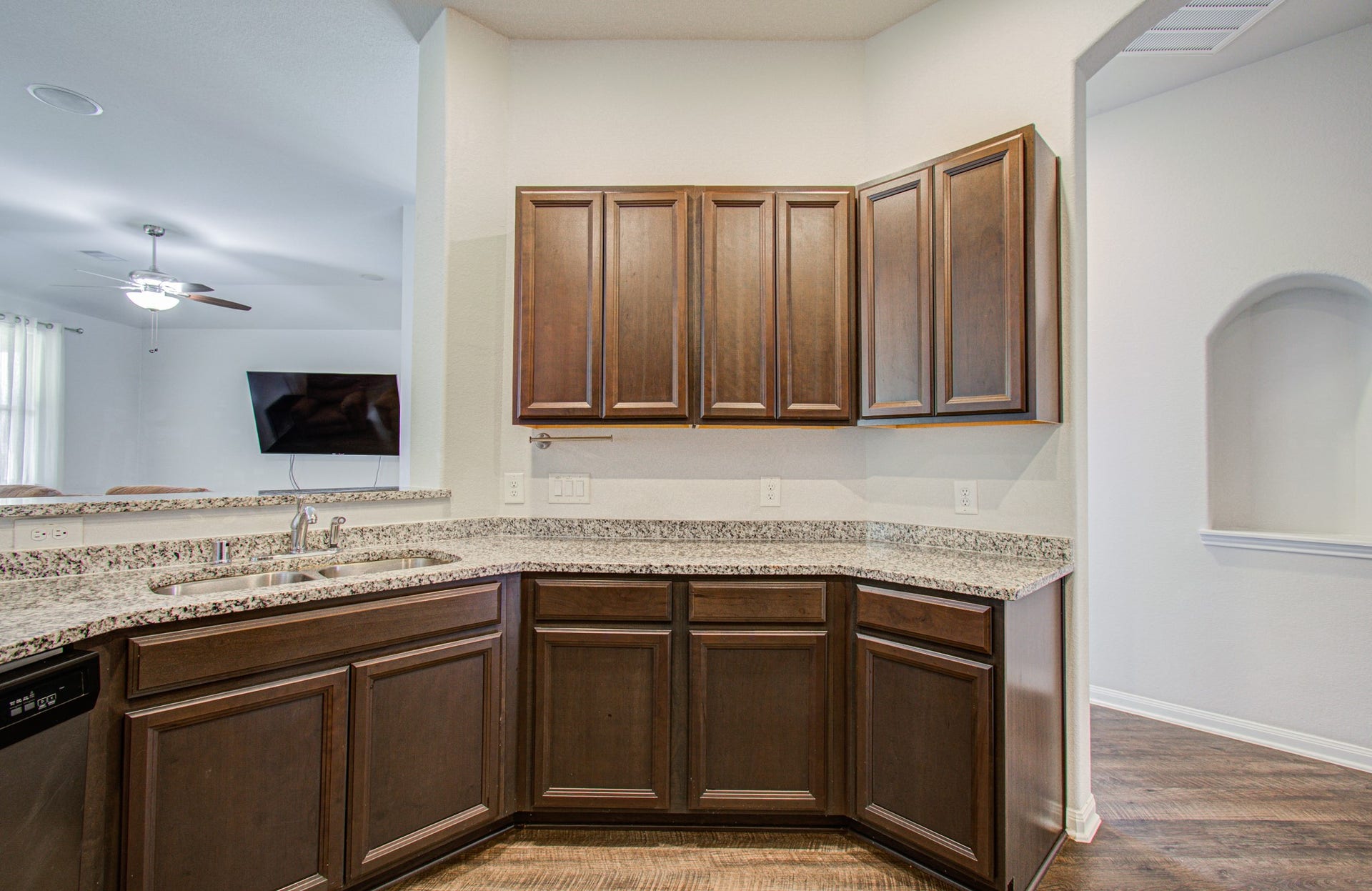 11064 Patriot Court, Cleveland, TX 77328 Elegant kitchen featuring rich wood cabinetry and sleek granite countertops, seamlessly connected to a spacious living area with modern amenities.