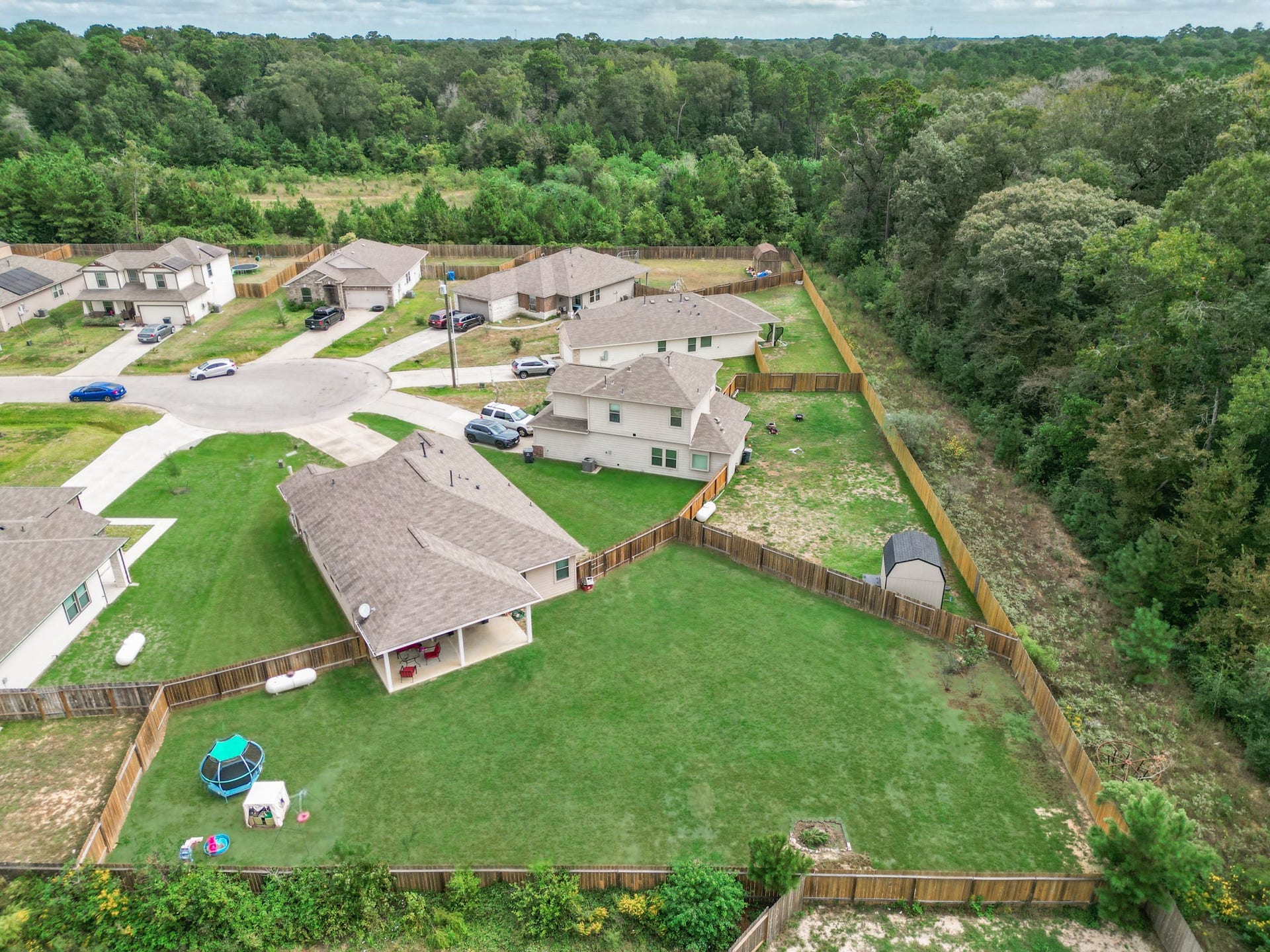 11064 Patriot Court, Cleveland, TX 77328 Spacious backyard with lush greenery, nestled in a quiet cul-de-sac and bordered by serene woods, perfect for privacy and outdoor activities.