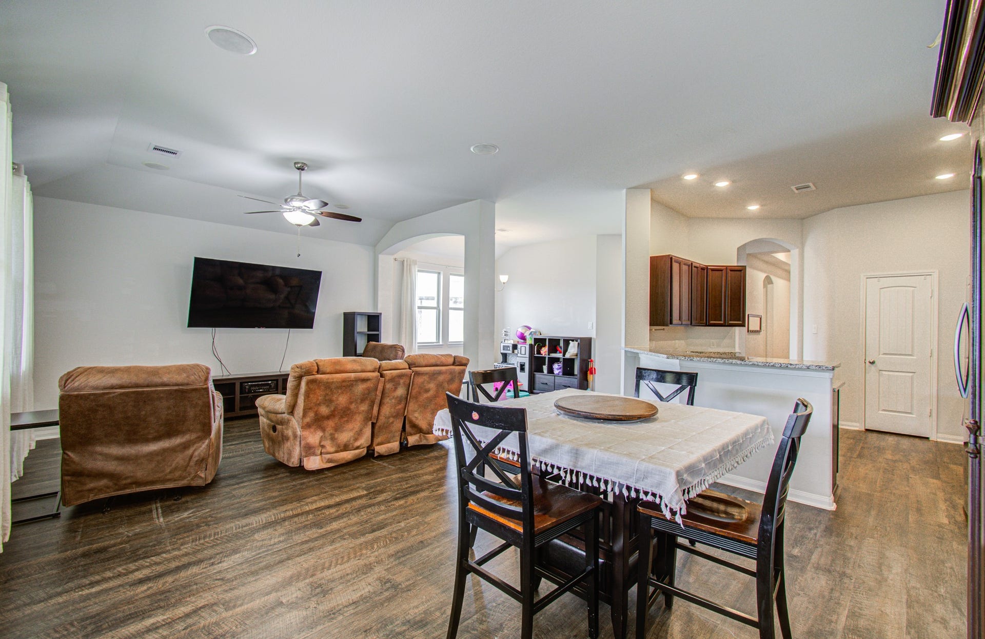 11064 Patriot Court, Cleveland, TX 77328 Open-concept living area with comfortable seating, a wall-mounted TV, and a cozy dining space. The kitchen features granite countertops and ample cabinetry, creating a perfect flow for entertaining.