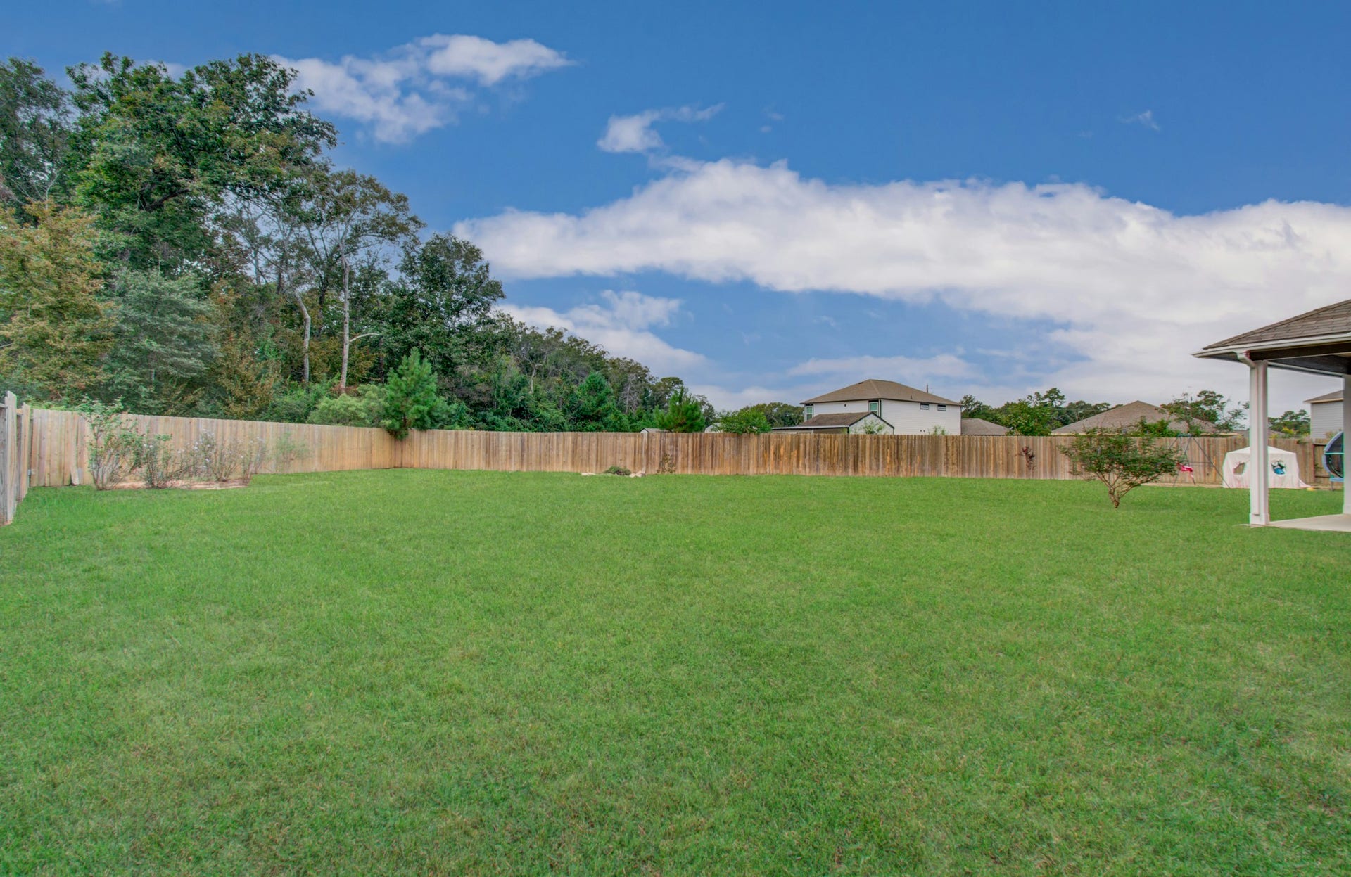 11064 Patriot Court, Cleveland, TX 77328 Expansive backyard with lush green lawn, perfect for outdoor activities and entertaining, bordered by a wooden fence for privacy.