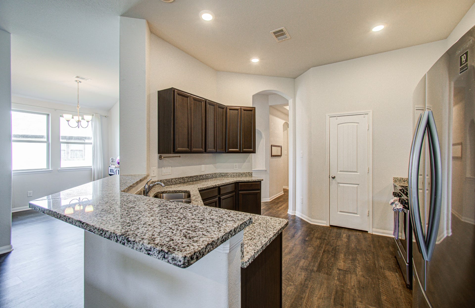 11064 Patriot Court, Cleveland, TX 77328 Spacious kitchen featuring sleek granite countertops, modern stainless steel appliances, and rich dark wood cabinetry, seamlessly flowing into a bright dining area.