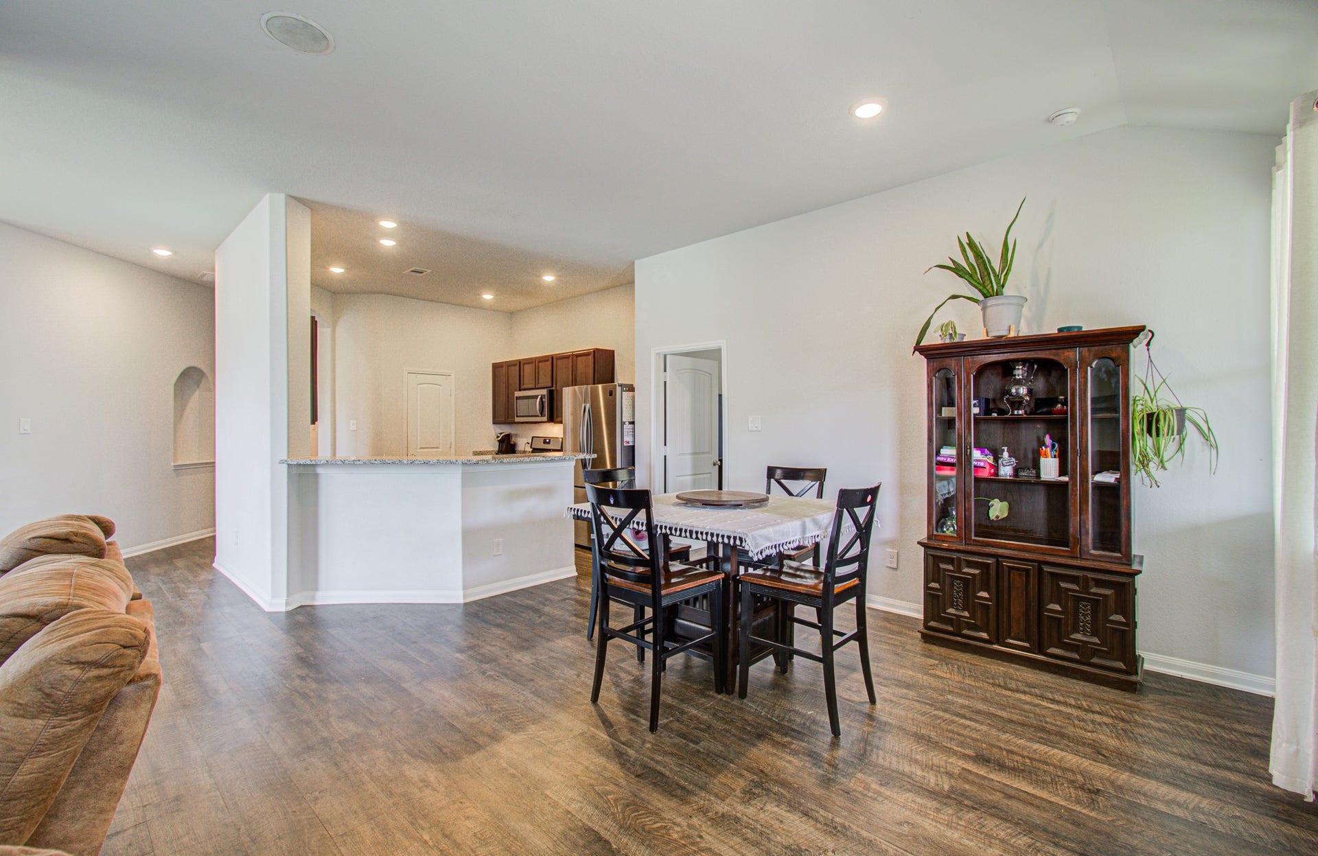 11064 Patriot Court, Cleveland, TX 77328 Spacious open-concept dining area with elegant wood flooring and ample natural light, seamlessly connected to a modern kitchen featuring granite countertops and stainless steel appliances.