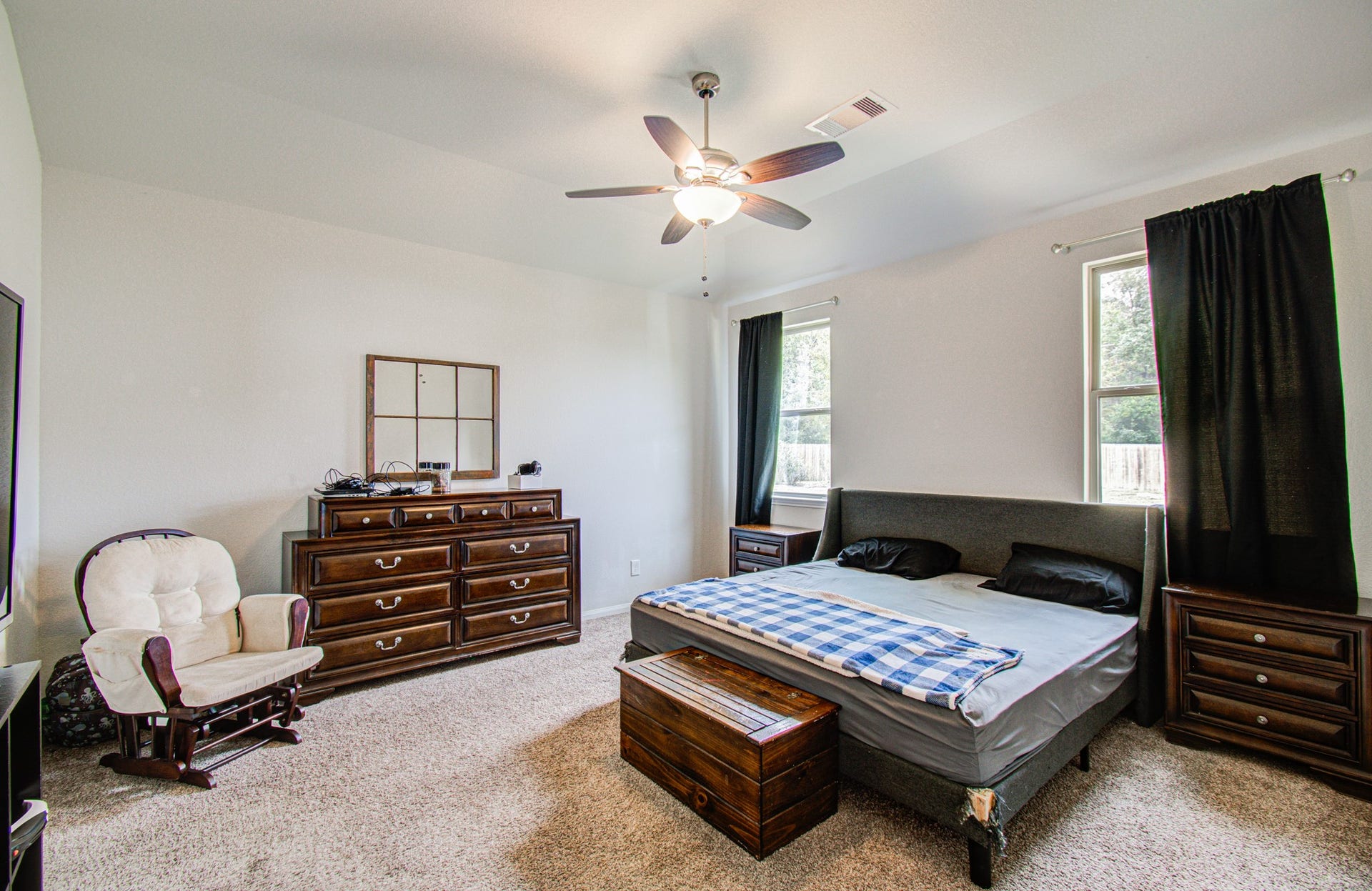 11064 Patriot Court, Cleveland, TX 77328 Spacious primary bedroom , featuring a ceiling fan, ample natural light from two windows.