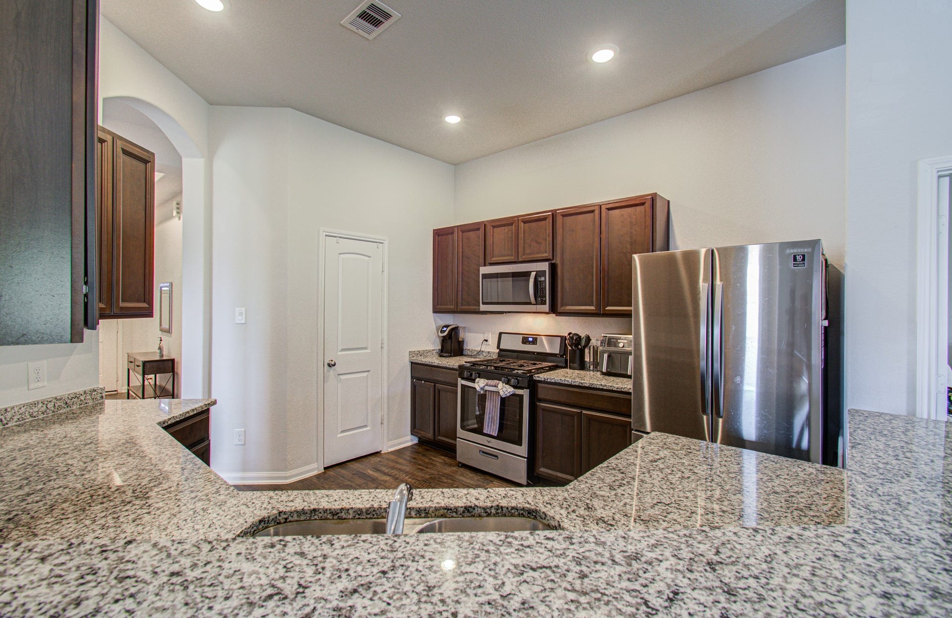 11064 Patriot Court, Cleveland, TX 77328 Modern kitchen with granite countertops, stainless steel appliances, and dark wood cabinetry, creating a stylish and functional space.