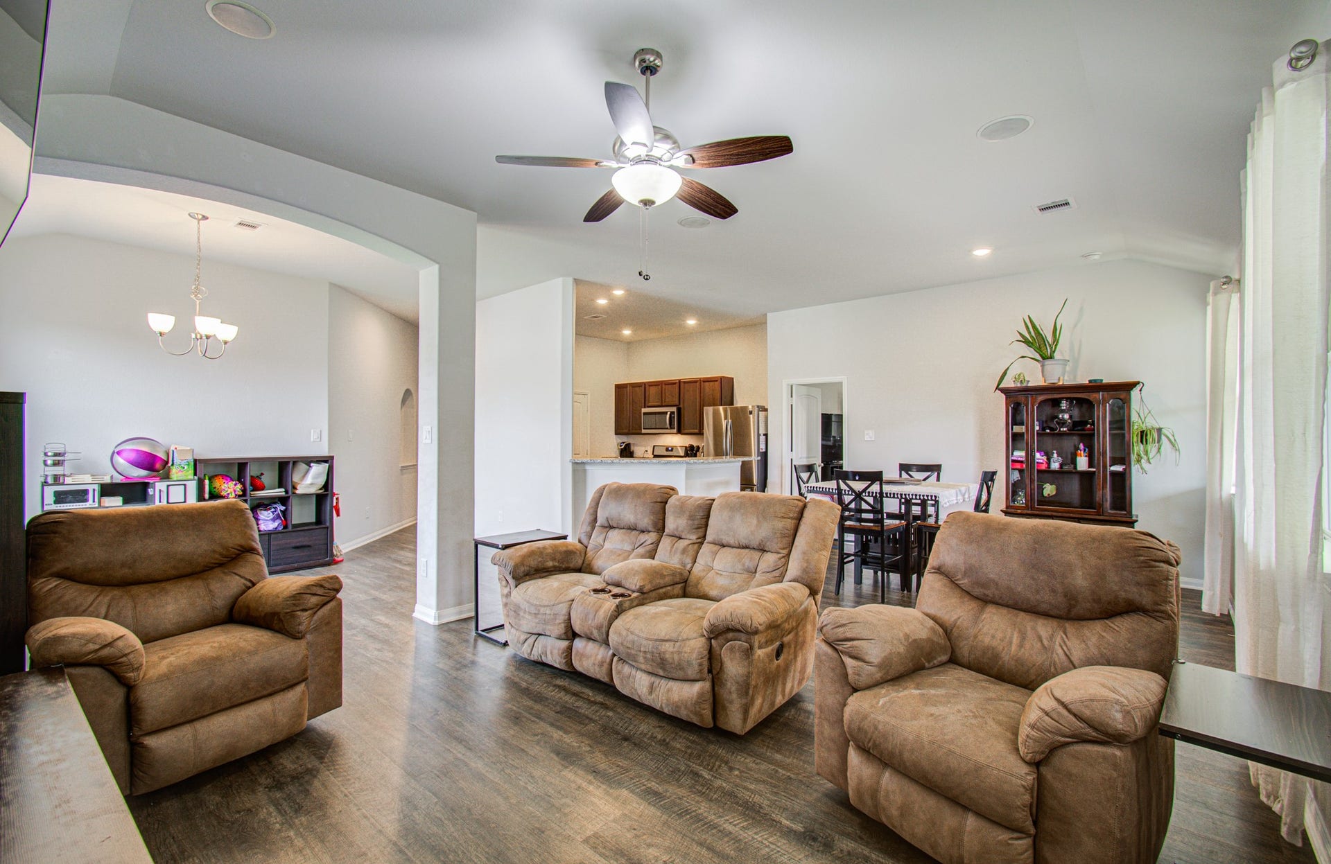 11064 Patriot Court, Cleveland, TX 77328 Spacious open-concept living area featuring plush seating, elegant ceiling fan, and seamless flow into the dining and kitchen spaces, perfect for family gatherings and entertaining.