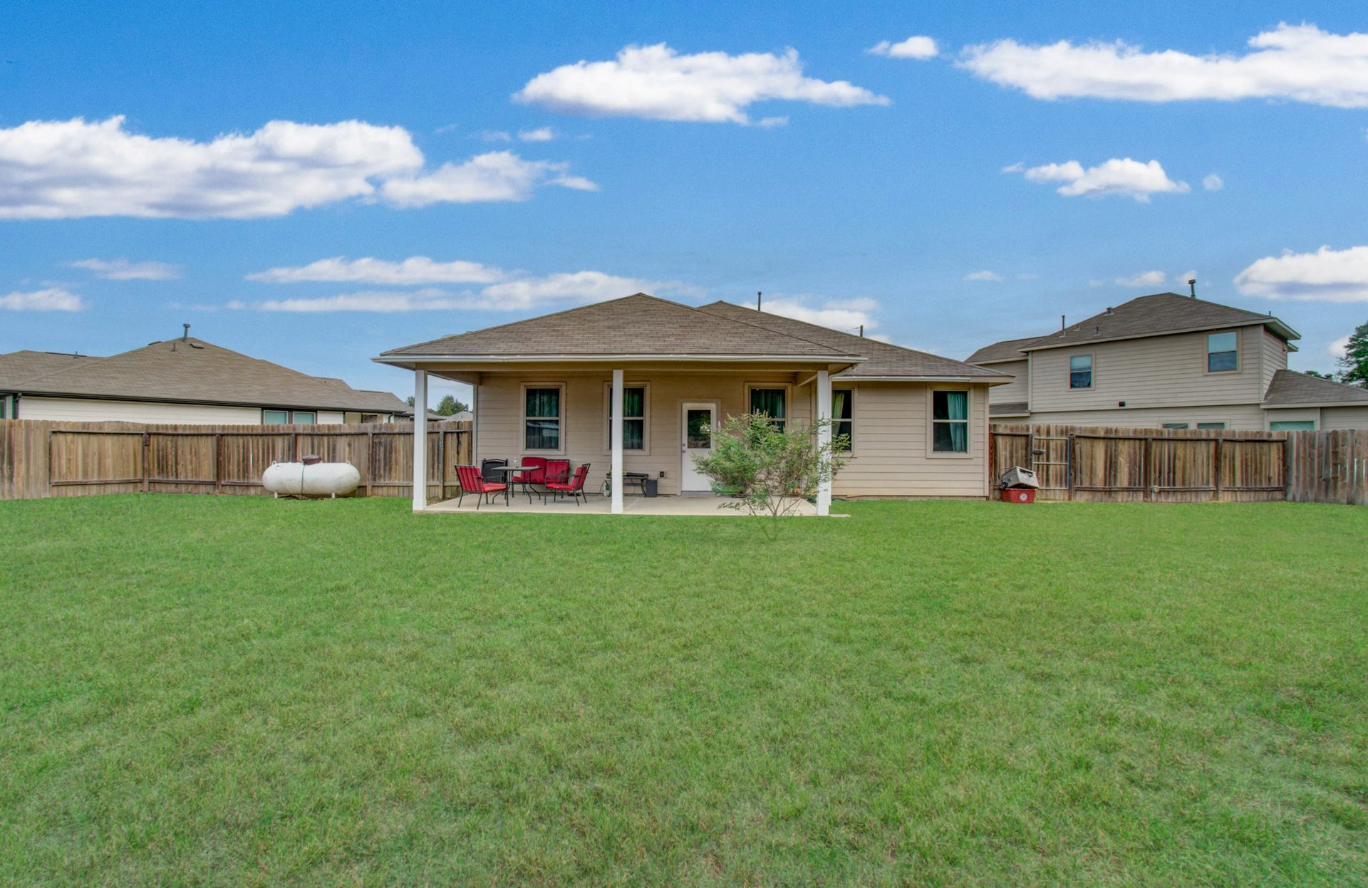 11064 Patriot Court, Cleveland, TX 77328 Spacious backyard featuring a covered patio, perfect for outdoor entertaining and relaxation, surrounded by a secure wooden fence.