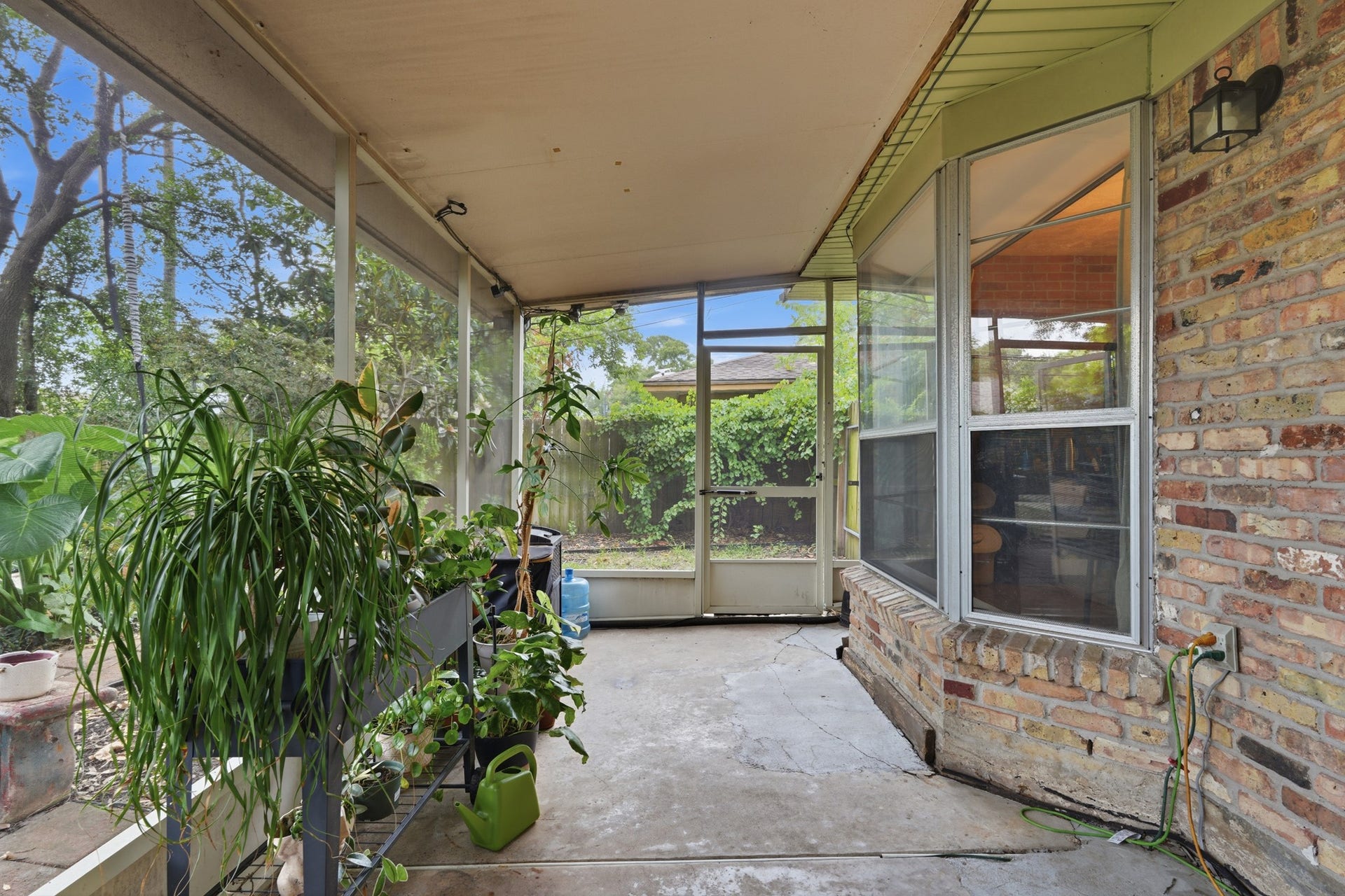 2216 Peach Lane, Pasadena, TX 77502 This inviting enclosed patio offers a serene, green oasis perfect for relaxing and enjoying the beauty of nature year-round.