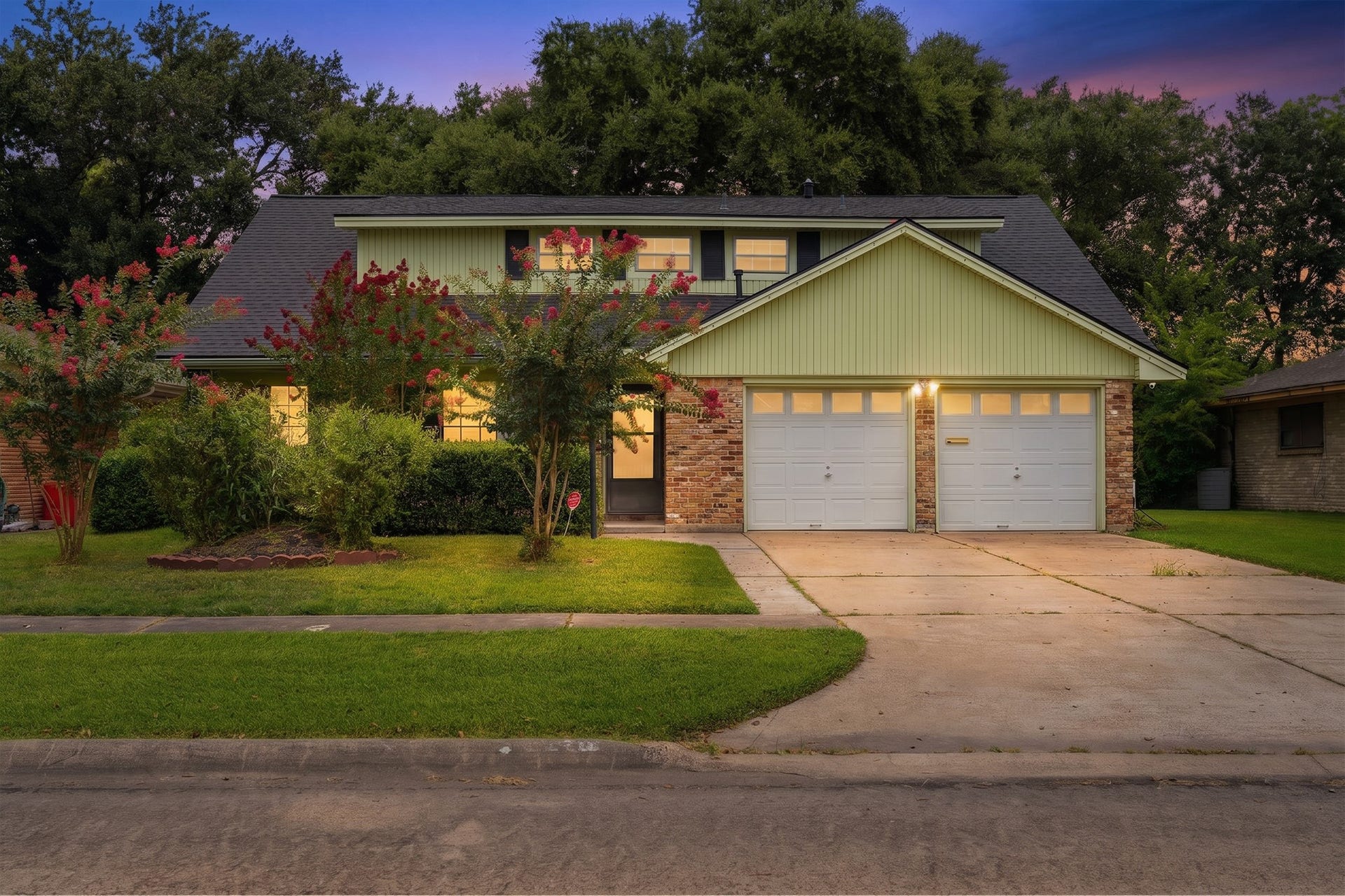 2216 Peach Lane, Pasadena, TX 77502 Charming two-story home with a brick and siding exterior, featuring a double garage and a well-maintained front yard with mature trees and shrubs.
