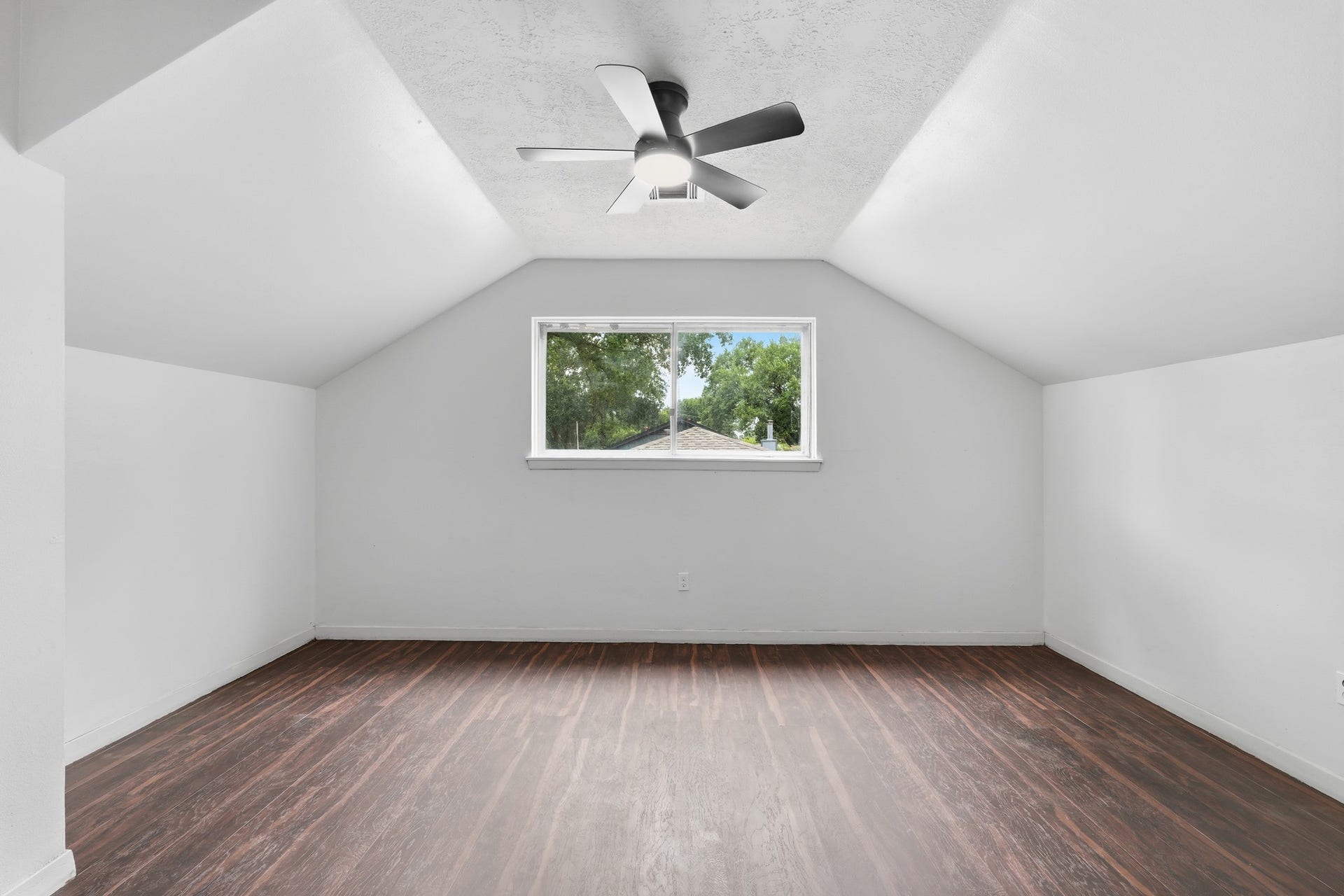 2216 Peach Lane, Pasadena, TX 77502 This bright spare room features sleek wooden floors, a modern ceiling fan, and a large window that invites natural light and scenic views, perfect for a cozy retreat or home office.