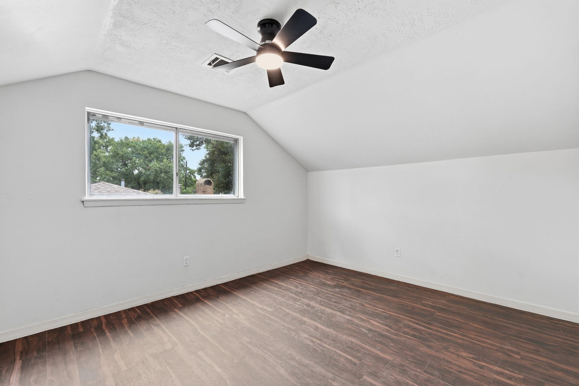 2216 Peach Lane, Pasadena, TX 77502 This inviting spare room boasts sleek hardwood floors, bright natural light from a large window, and a modern ceiling fan, offering the perfect canvas for your creative touch.