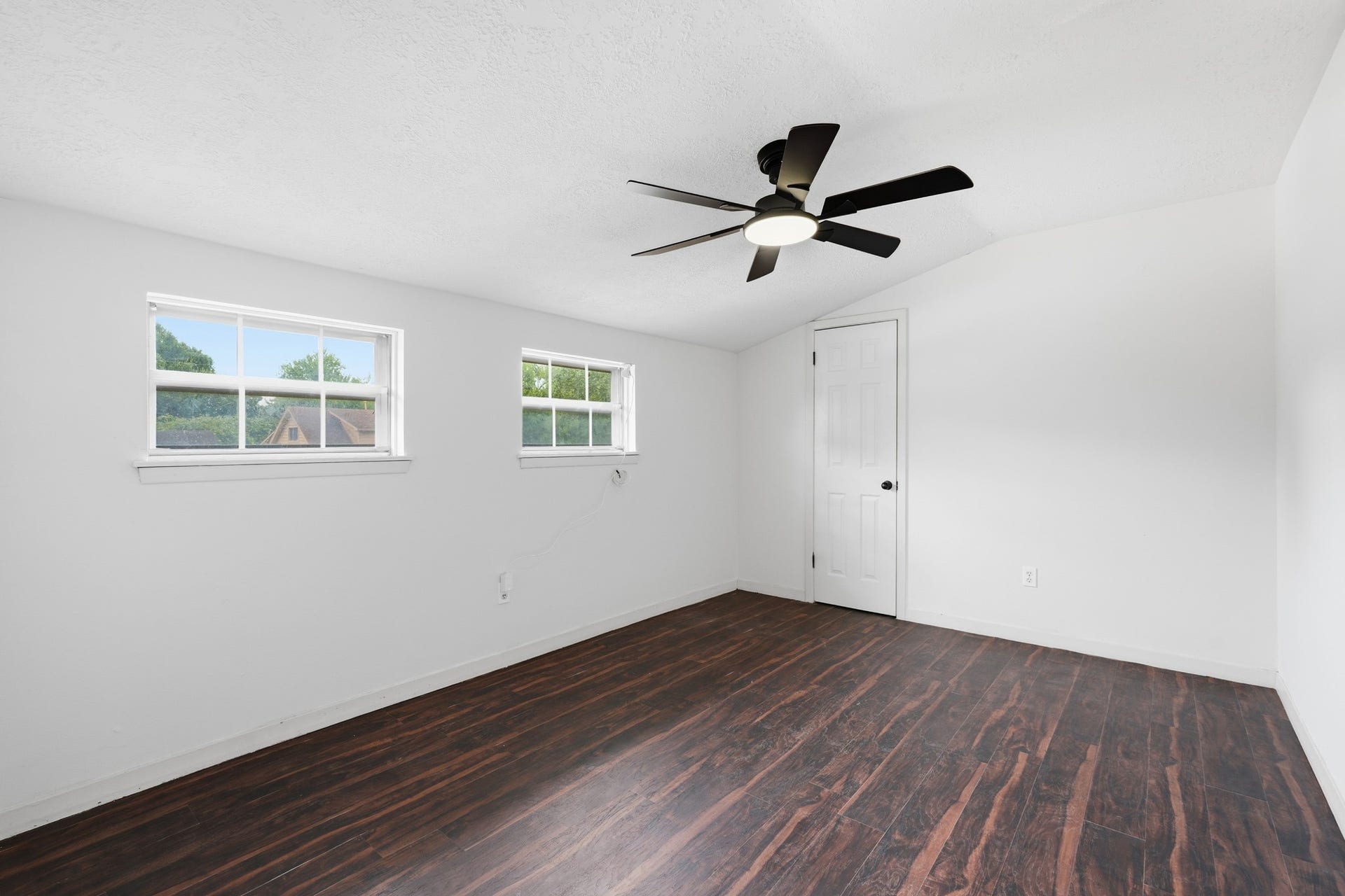 2216 Peach Lane, Pasadena, TX 77502 This inviting spare room boasts rich wood floors, fresh white walls, ample natural light, and a sleek ceiling fan, offering a versatile space perfect for relaxation or creativity.
