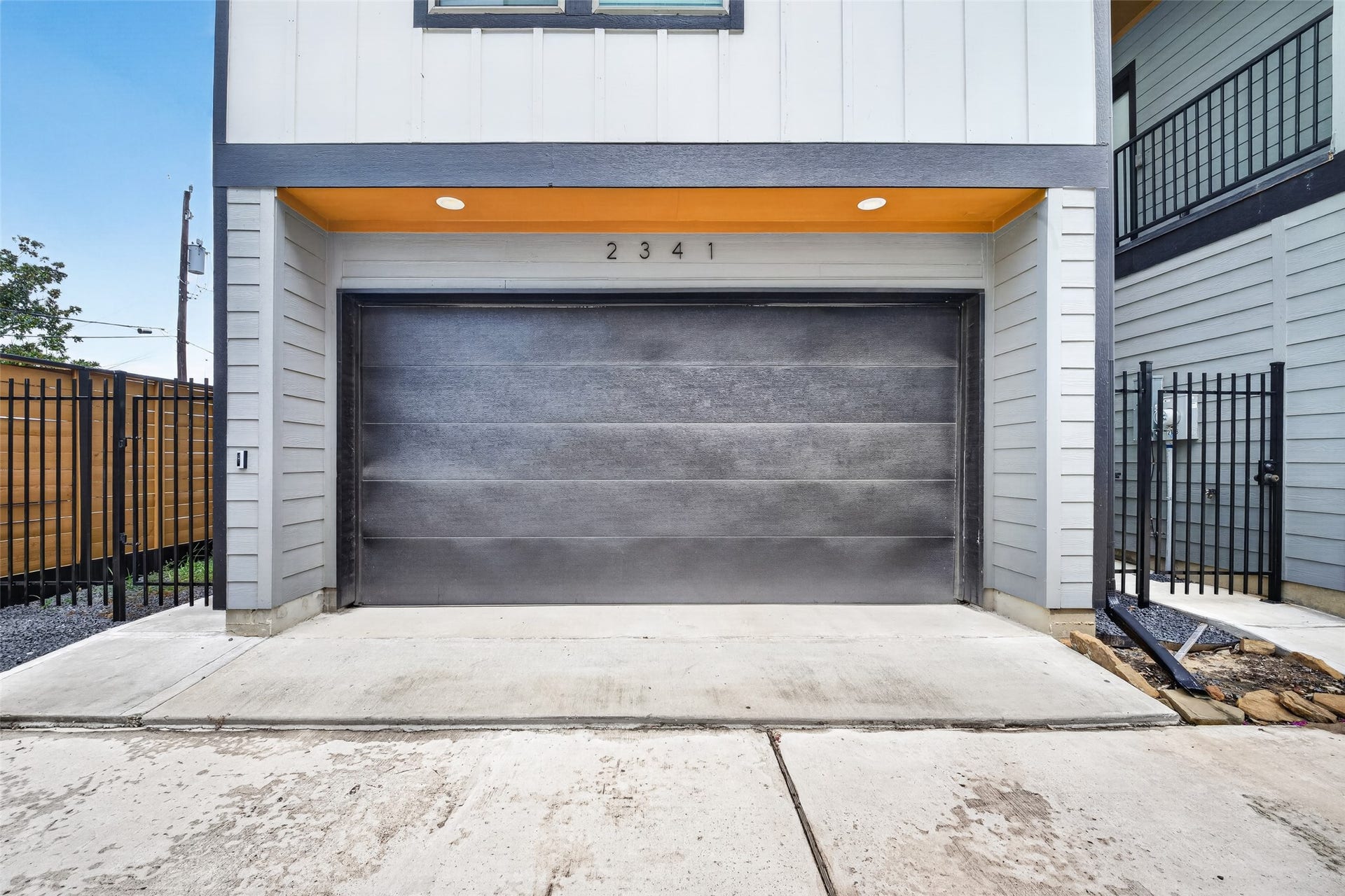 Clean exterior lines lead down to the two-car garage, illuminated by integrated overhead beam lighting.
