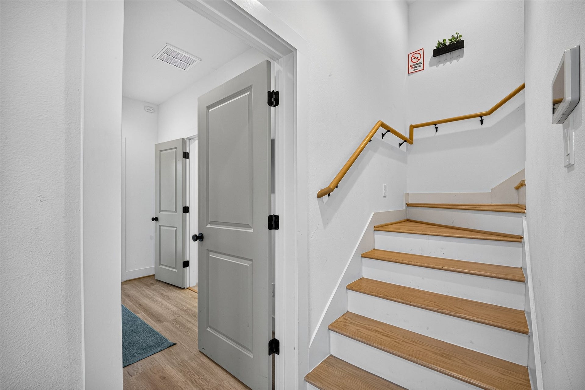 Inside the entry, rich wooden treads contrast against white risers, guiding the eye up a winding stairwell toward the upper levels.