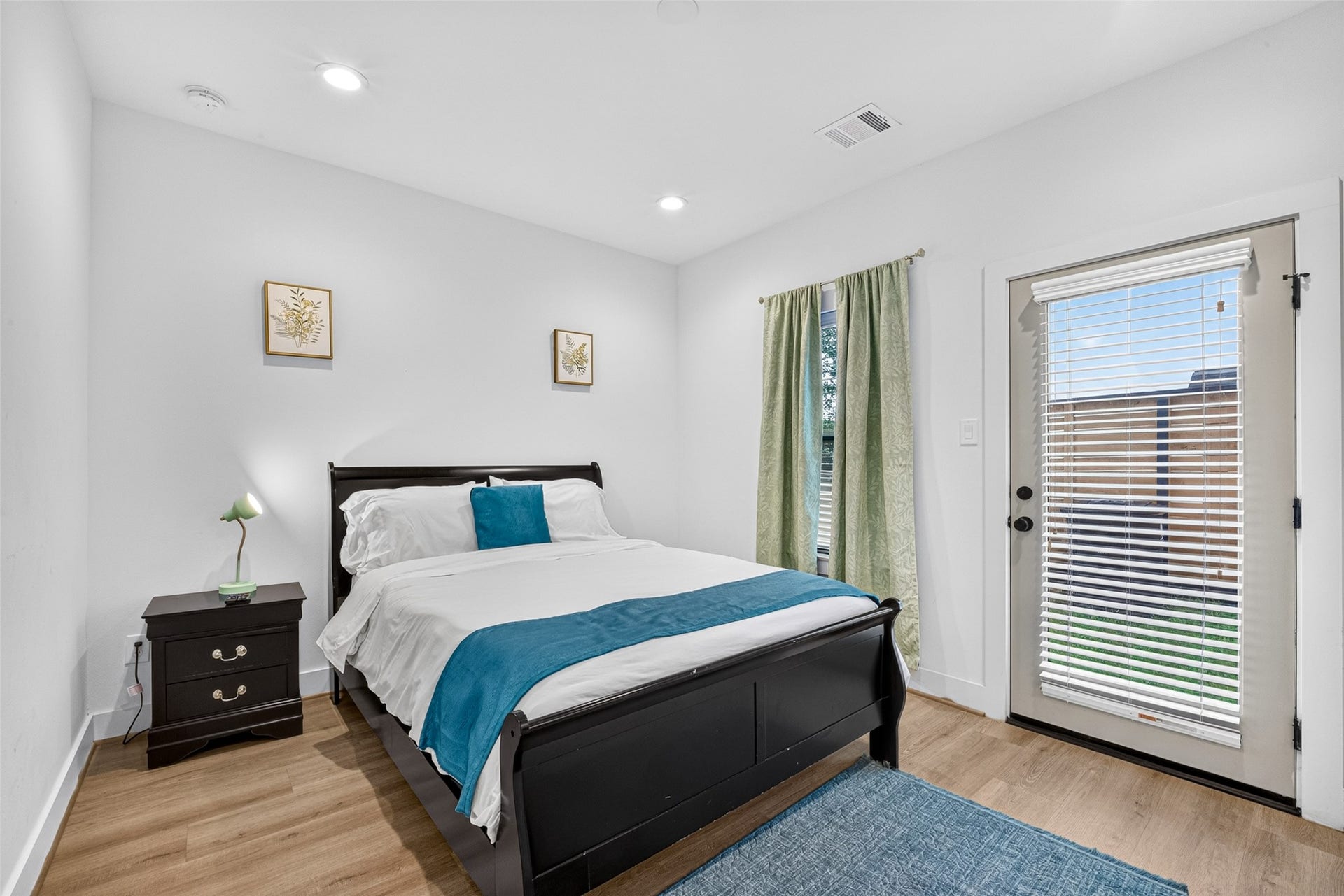 Sunlight streams across warm hardwoods in this ground-floor bedroom, complete with a glass-paneled door that opens directly to the private yard space.
