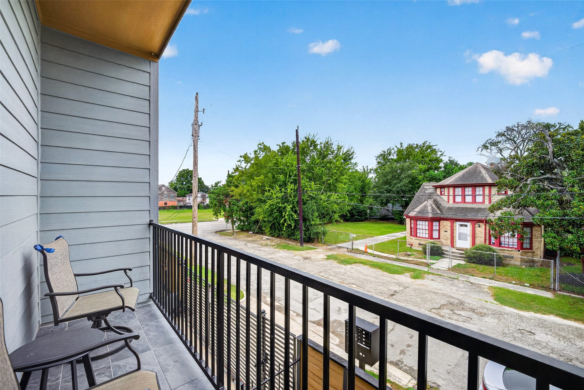 The balcony provides a quiet vantage point over the tree-lined neighborhood streetscape, offering ample space for lounge seating.