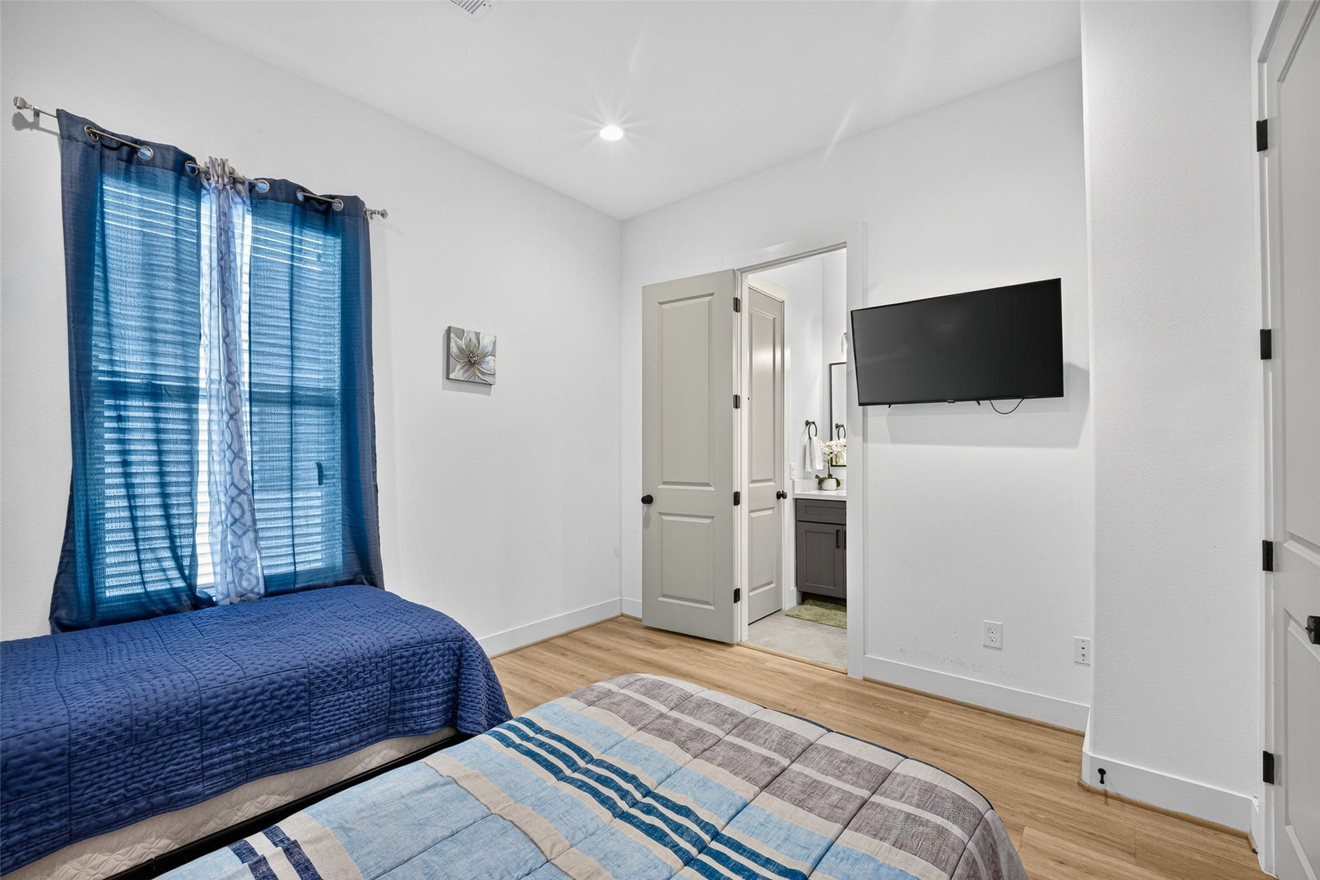 Natural light fills this upper-level bedroom, highlighting the clean palette and warm flooring while the private en-suite adds an extra measure of convenience.