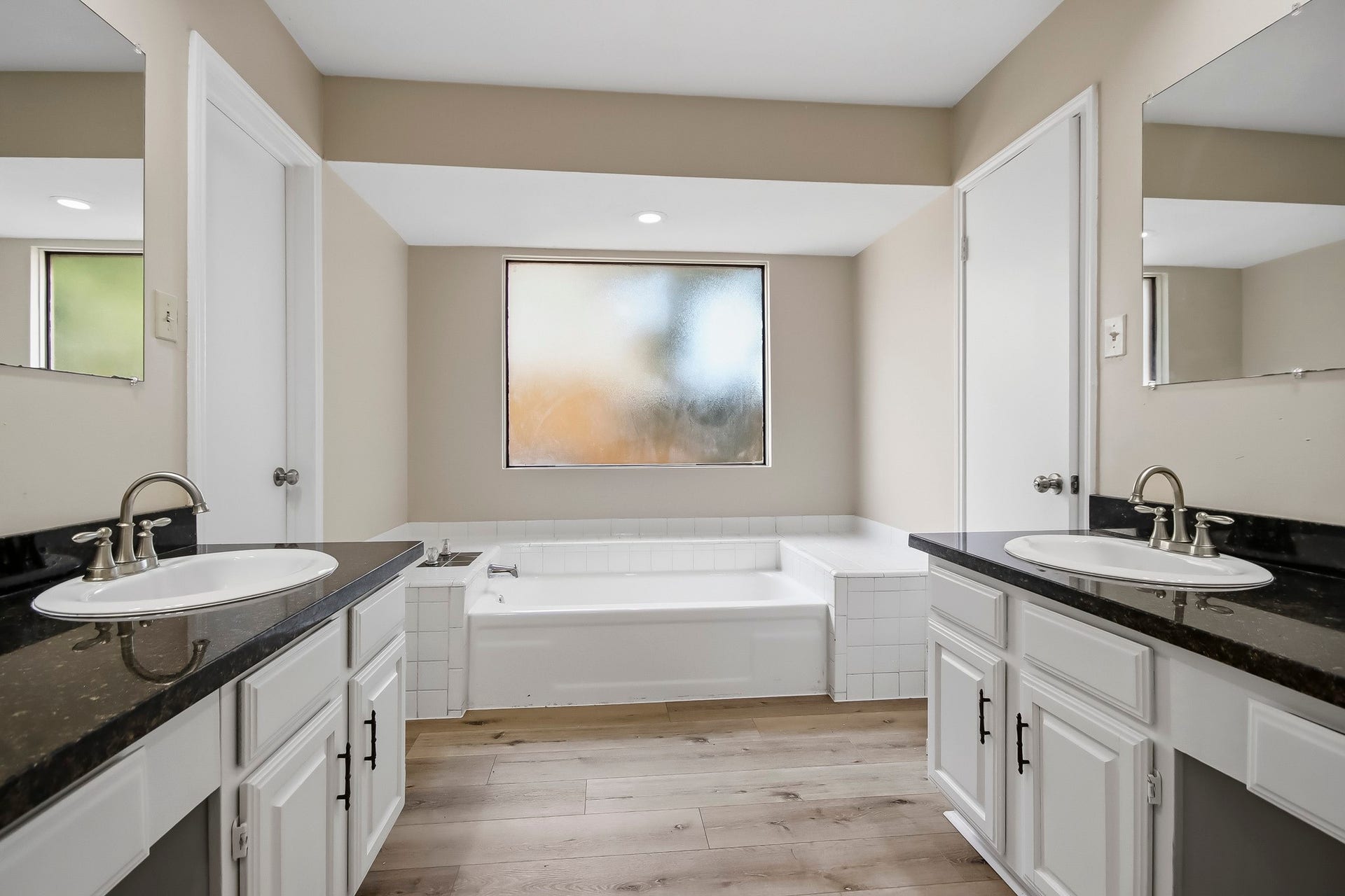 8807 Lakeside Forest Drive, Houston, TX 77088 Primary ensuite bathroom featuring dual vanities, dark countertops, and a soaking tub.