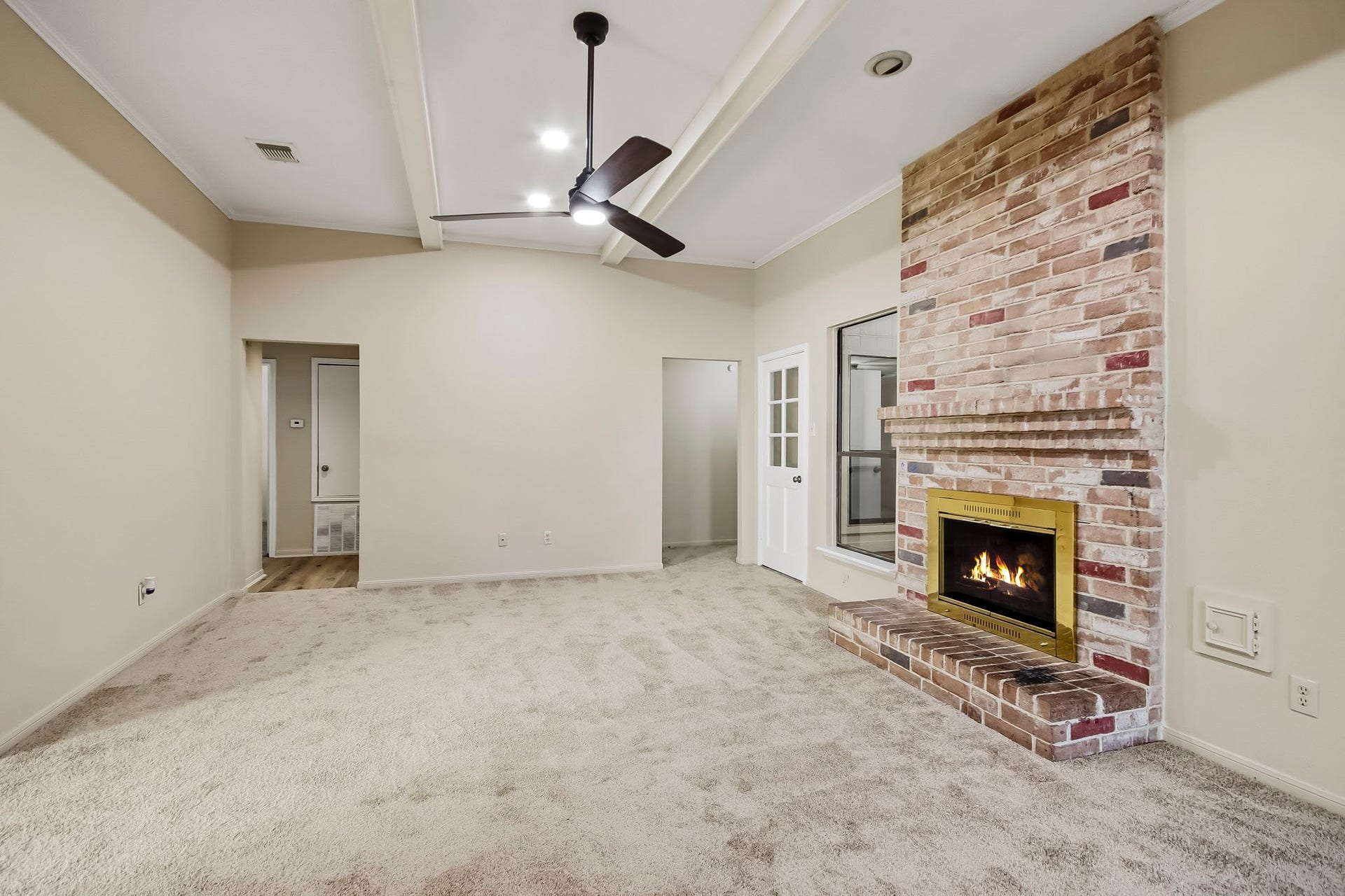 8807 Lakeside Forest Drive, Houston, TX 77088 Spacious living room featuring a floor-to-ceiling brick fireplace, high ceilings, and a ceiling fan.