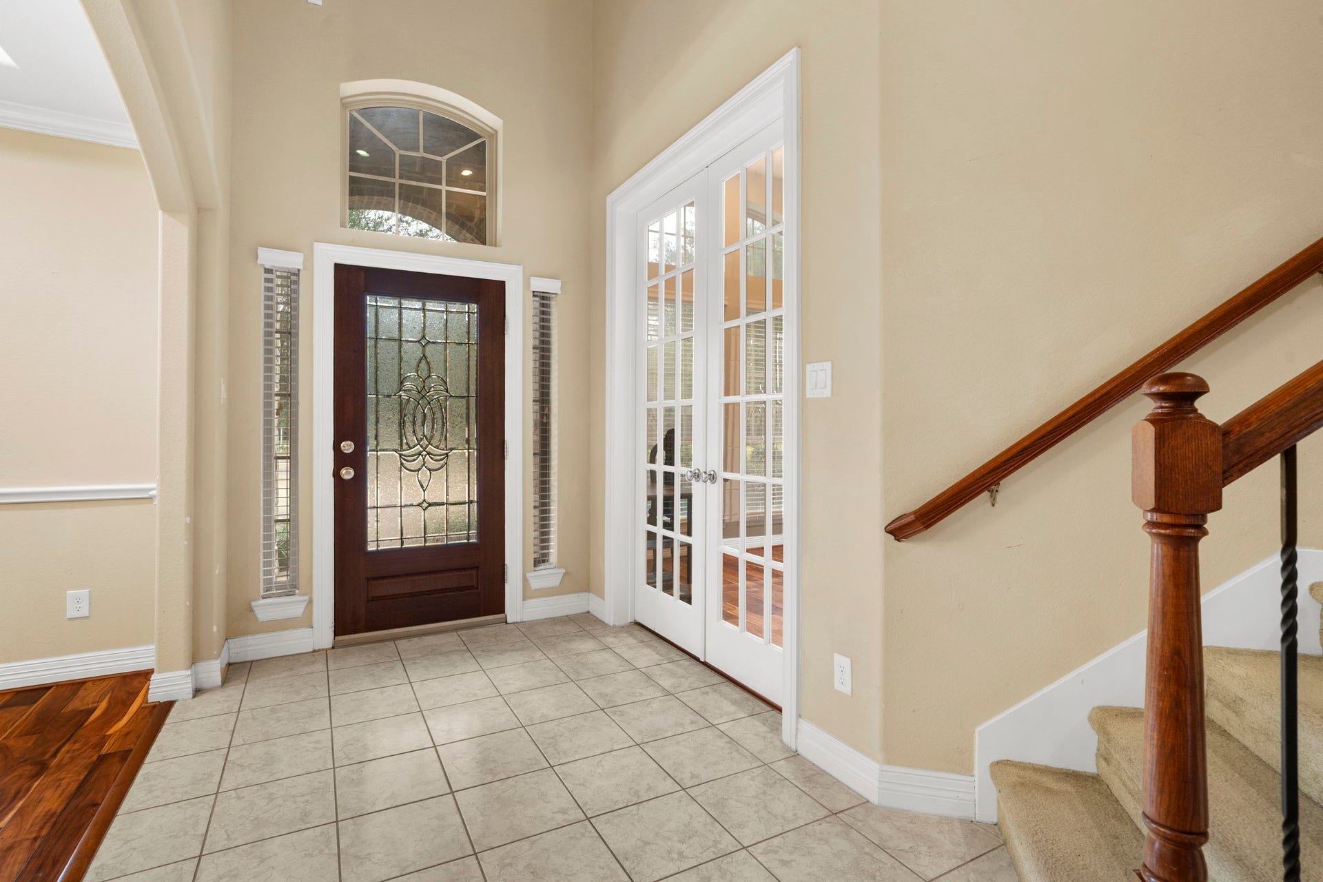 5515 Mangrove Creek Lane, Sugar Land, TX 77479 Wood front door accented with decorative leaded glass, a transom window above, and sidelights on either side.