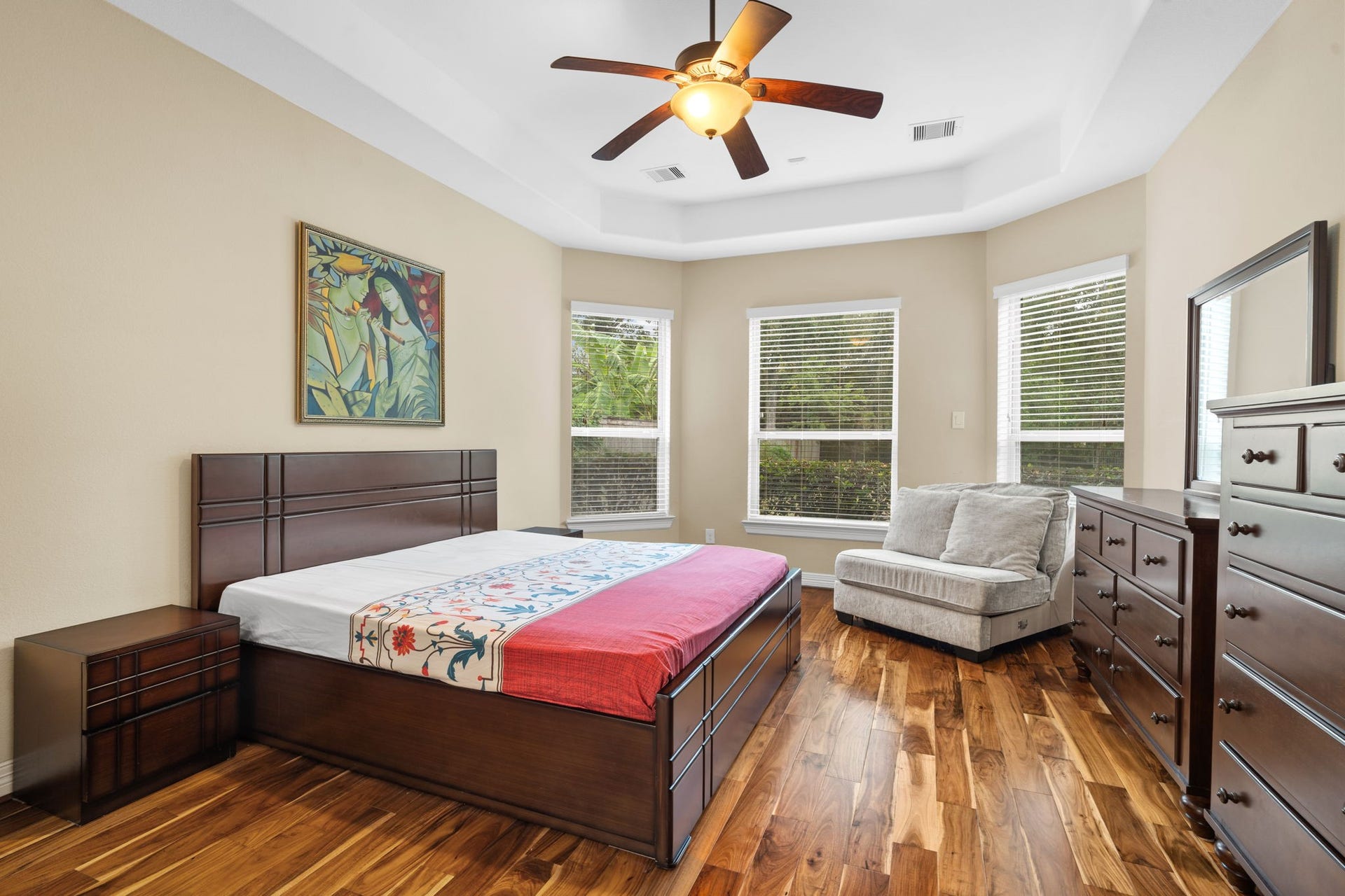 5515 Mangrove Creek Lane, Sugar Land, TX 77479 Step inside the spacious, first-floor primary bedroom featuring an elegant tray ceiling, wood flooring, relaxing window views, and an en-suite bathroom.