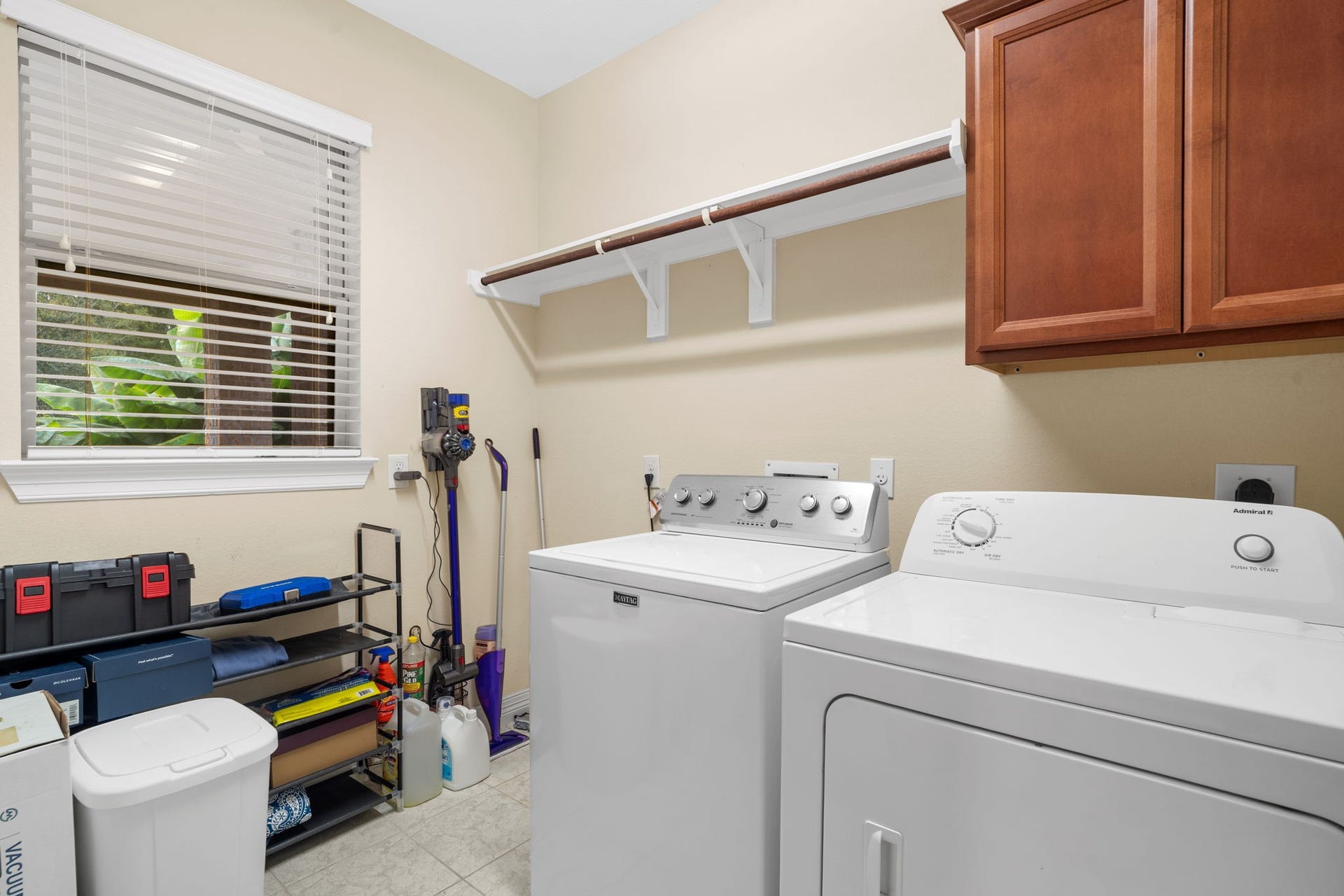 5515 Mangrove Creek Lane, Sugar Land, TX 77479 Convenient in-home laundry room with a storage cabinet, hanging rack, shelf, and space for a full-sized refrigerator.