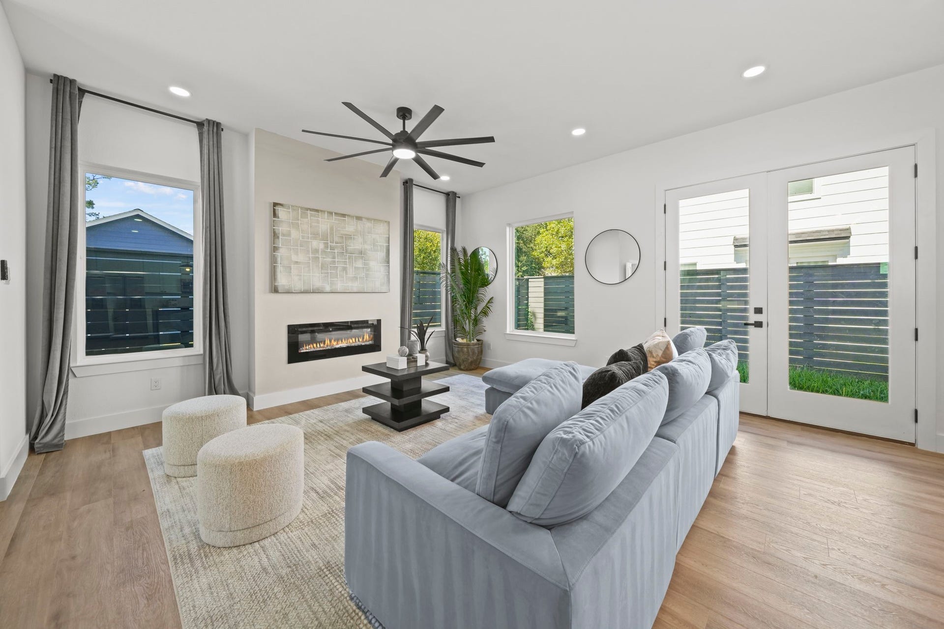 The living room is well lit with large windows and a cozy electric fireplace for evenings.