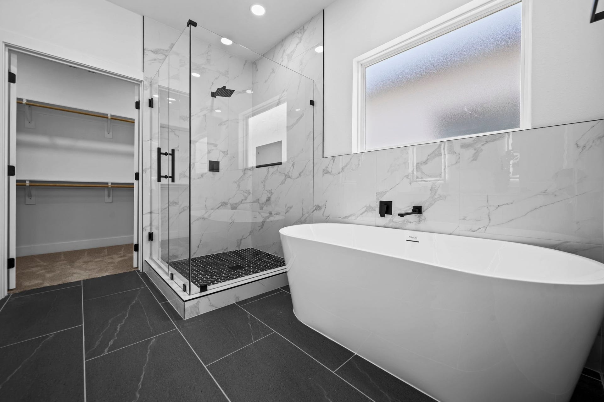 Gorgeous primary bathroom with marble floors, a walk in shower, and huge soaker tub connecting to the walk in closet.