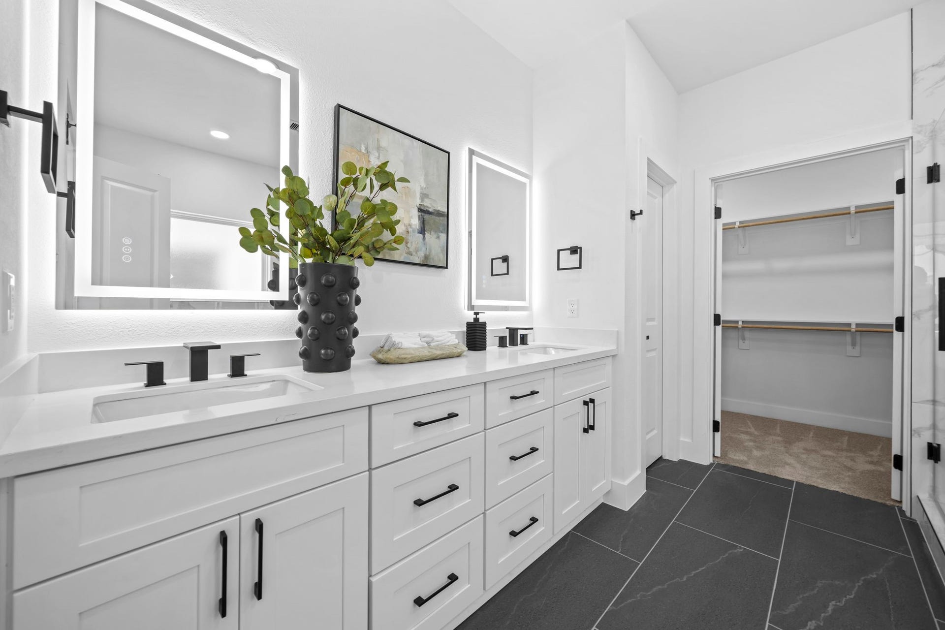 The primary en-suite with dual sinks and vanity mirrors connecting to the walk in closet.