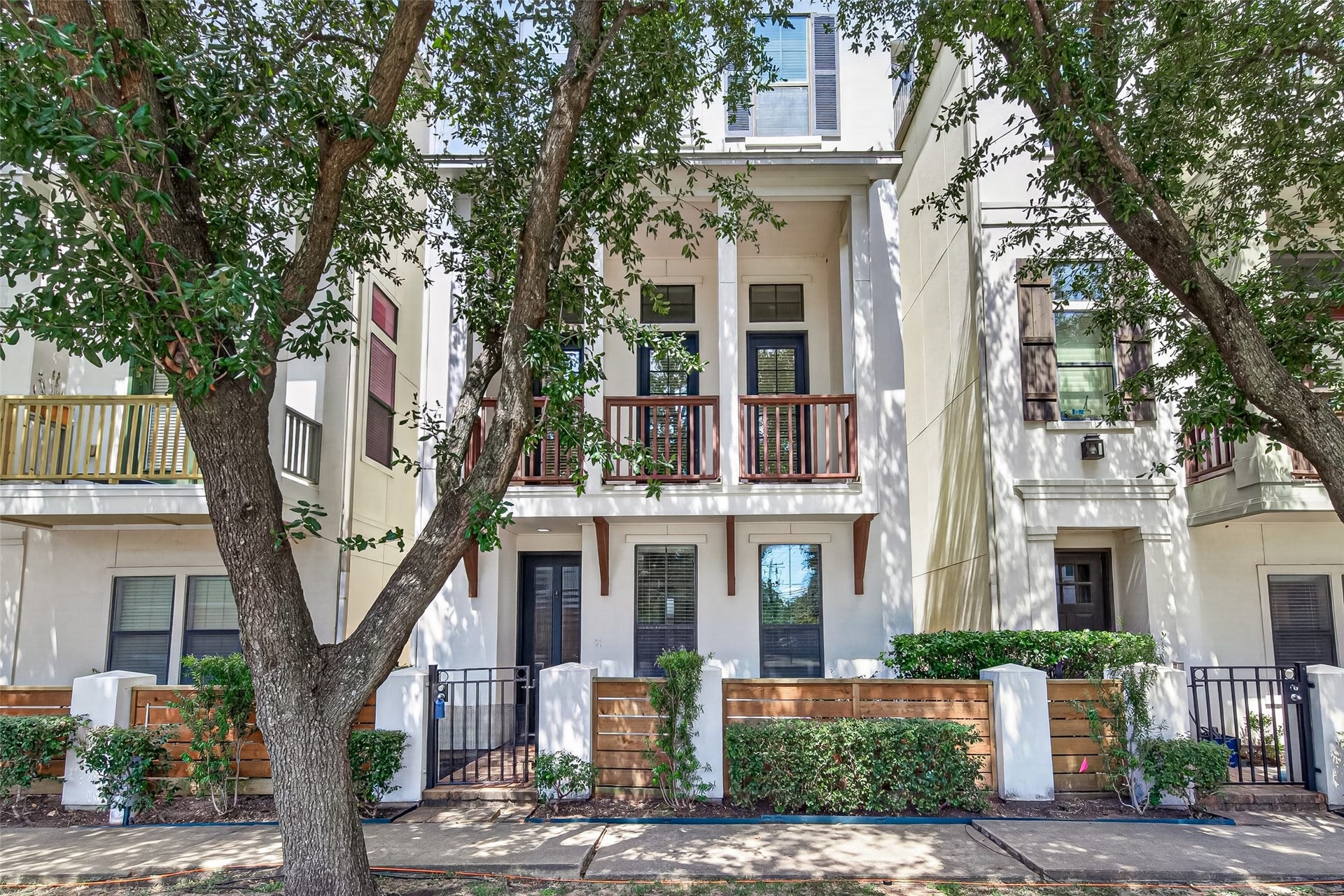 6610 Toledo Street, Houston, TX 77008 Charming three-story townhouse with elegant balconies and a welcoming front patio, nestled among mature trees for added privacy and curb appeal.
