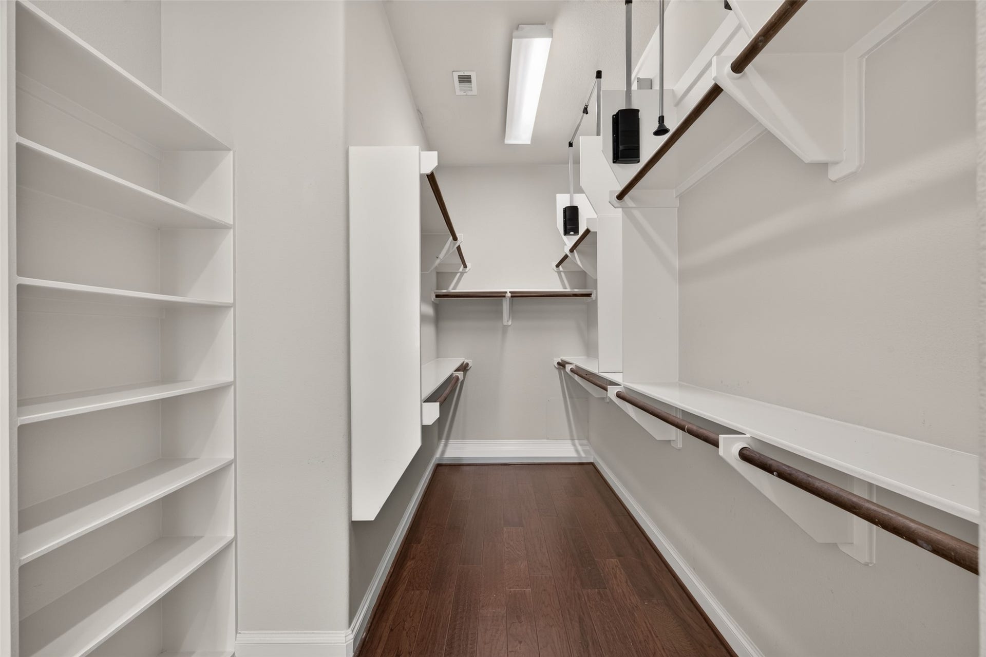 6610 Toledo Street, Houston, TX 77008 Spacious walk-in closet with ample shelving and hanging space, featuring sleek wooden floors and bright overhead lighting.