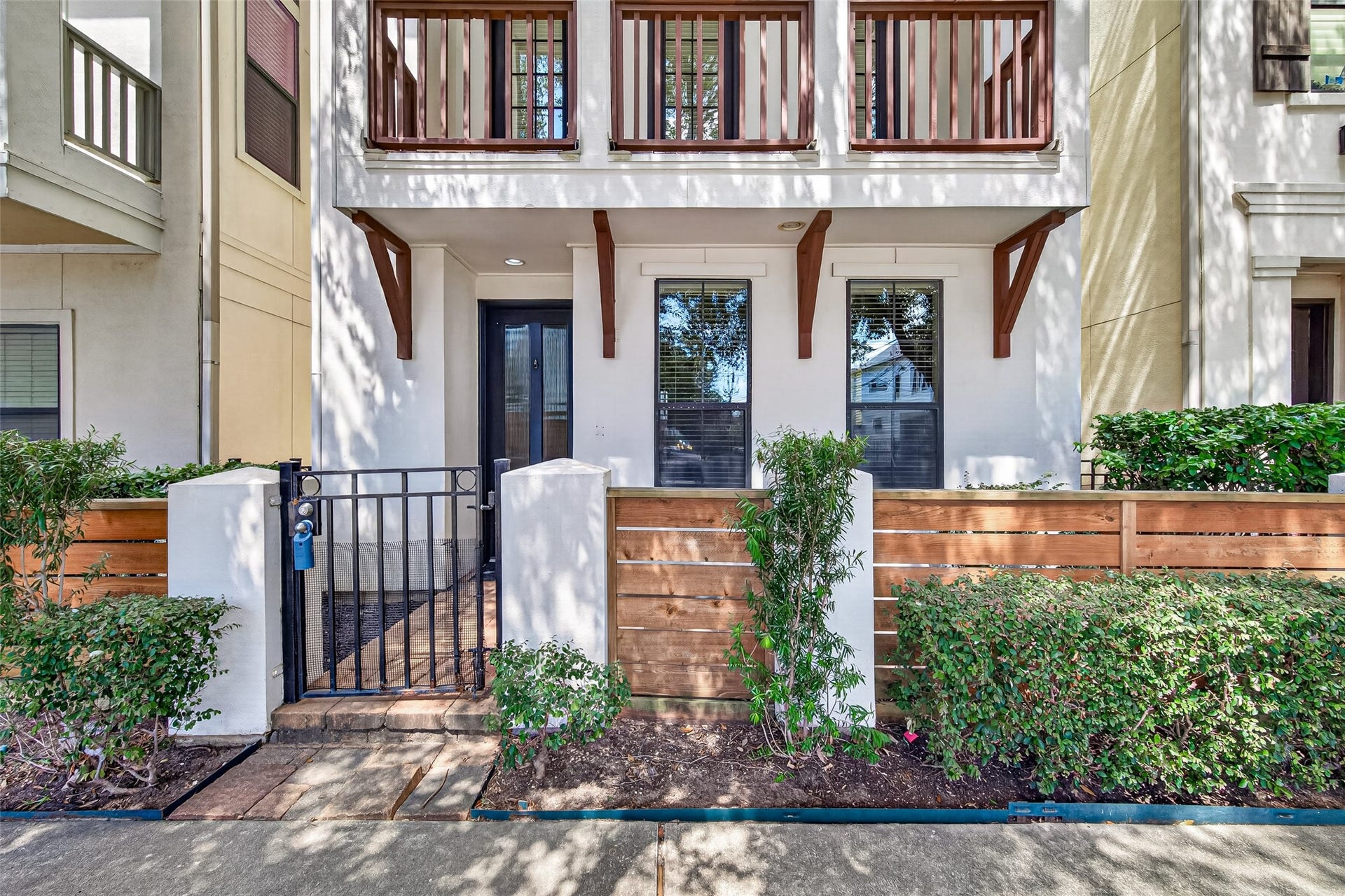 6610 Toledo Street, Houston, TX 77008 Charming townhouse with a welcoming gated entrance, elegant balcony, and lush landscaping for added privacy.