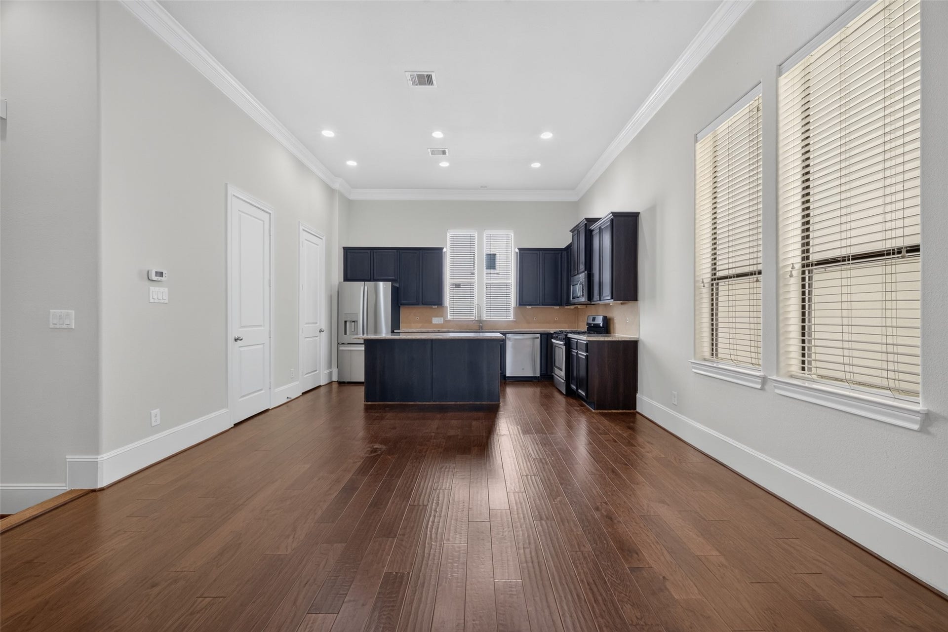 6610 Toledo Street, Houston, TX 77008 Spacious kitchen with elegant dark cabinetry, stainless steel appliances, and rich hardwood flooring, all bathed in natural light from large windows.
