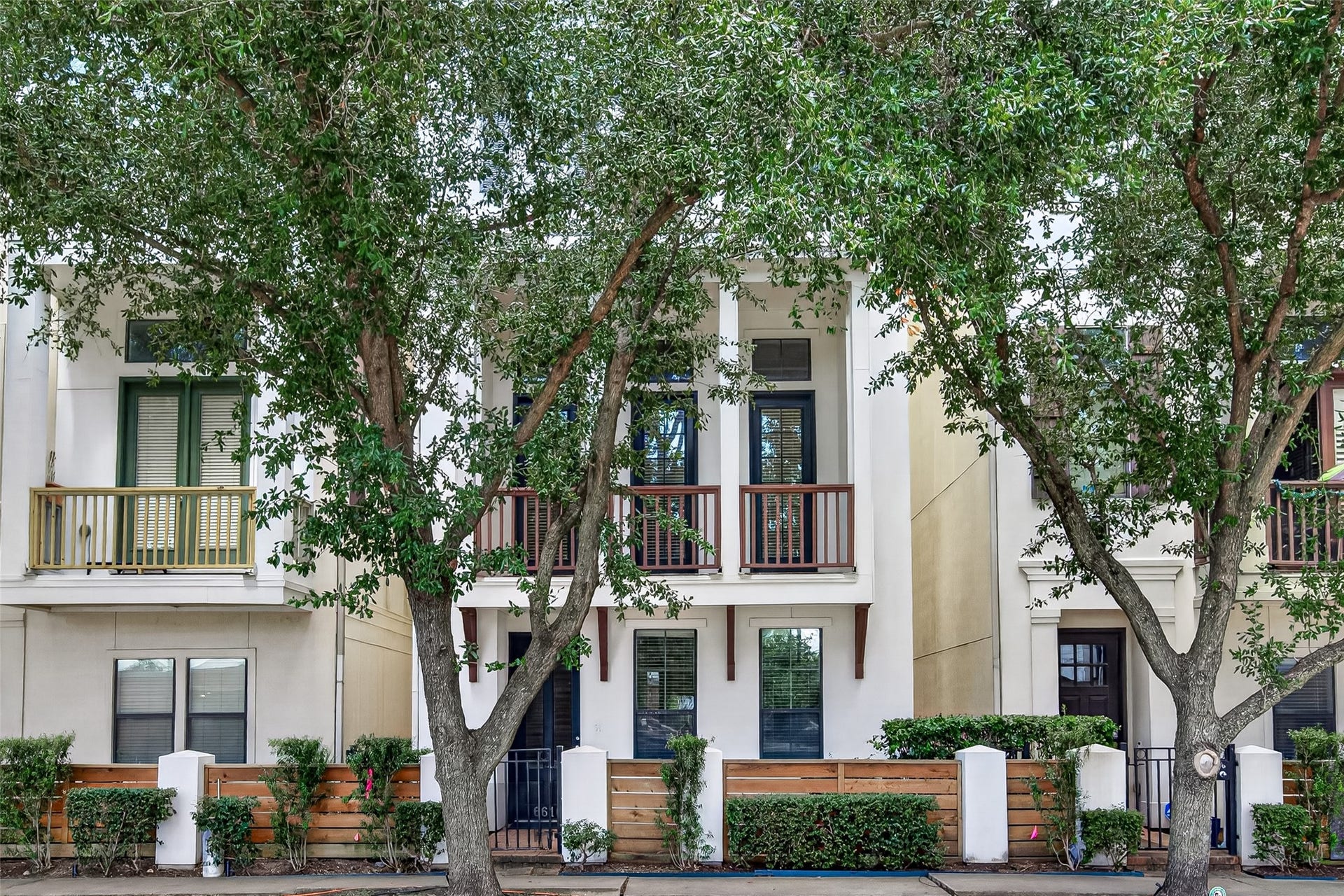 6610 Toledo Street, Houston, TX 77008 Charming townhouse with a welcoming facade, featuring large windows and a private balcony, nestled among mature trees for added privacy and shade.