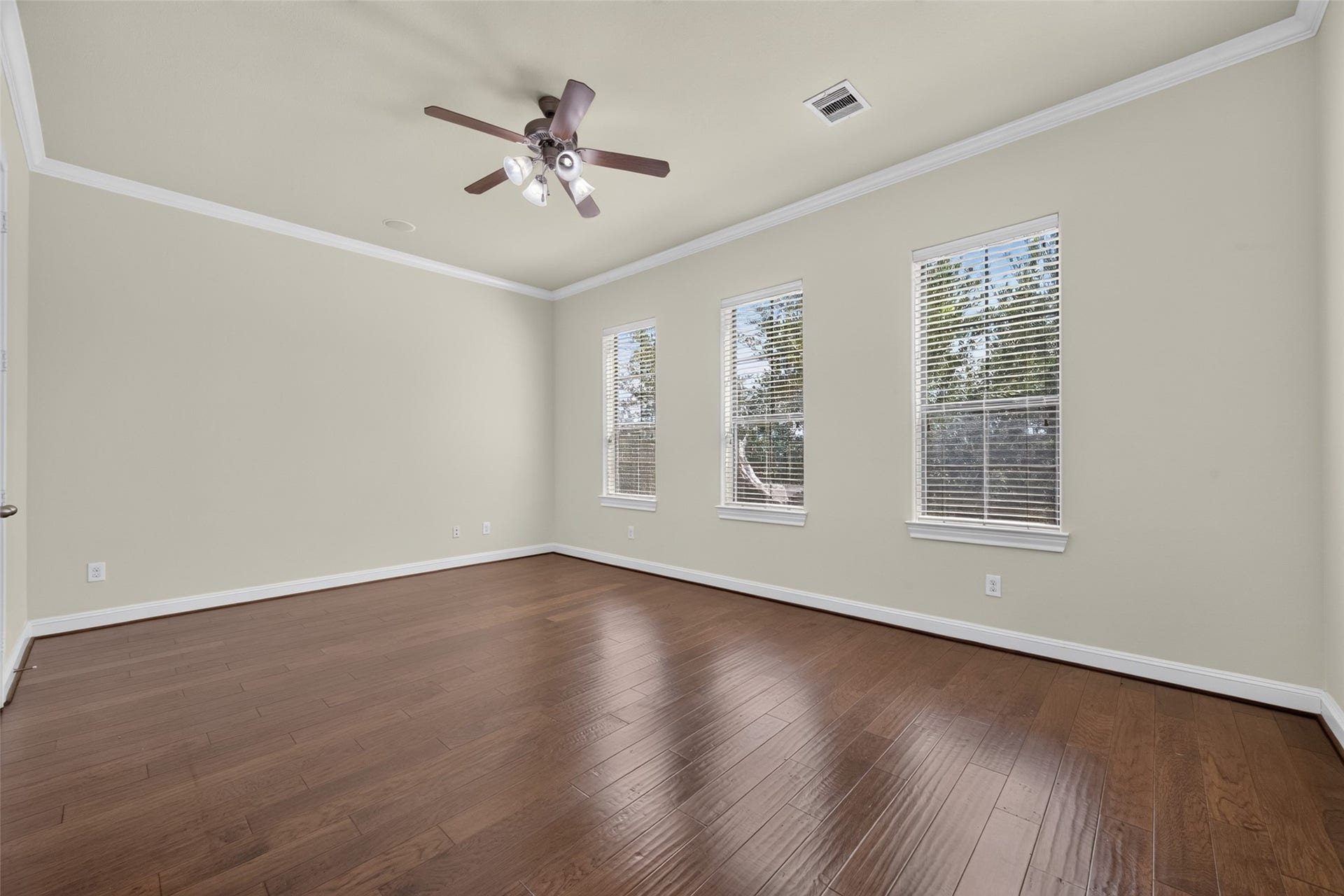 6610 Toledo Street, Houston, TX 77008 Spacious room with elegant hardwood floors, abundant natural light from three large windows, and a stylish ceiling fan.
