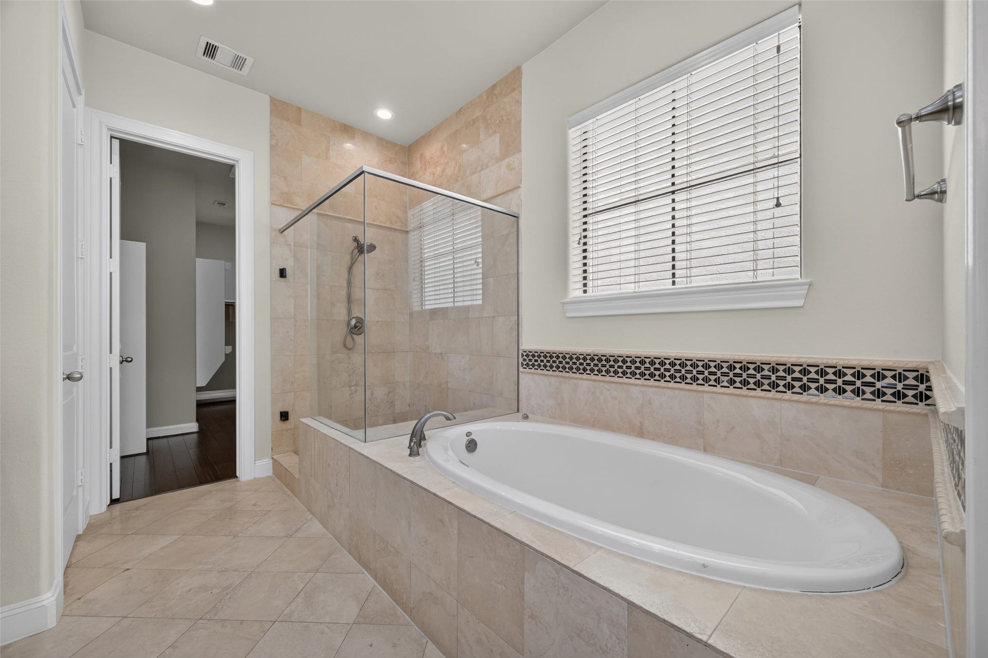 6610 Toledo Street, Houston, TX 77008 Elegant bathroom featuring a luxurious soaking tub and a spacious glass-enclosed shower, accented by stylish tile work and abundant natural light.