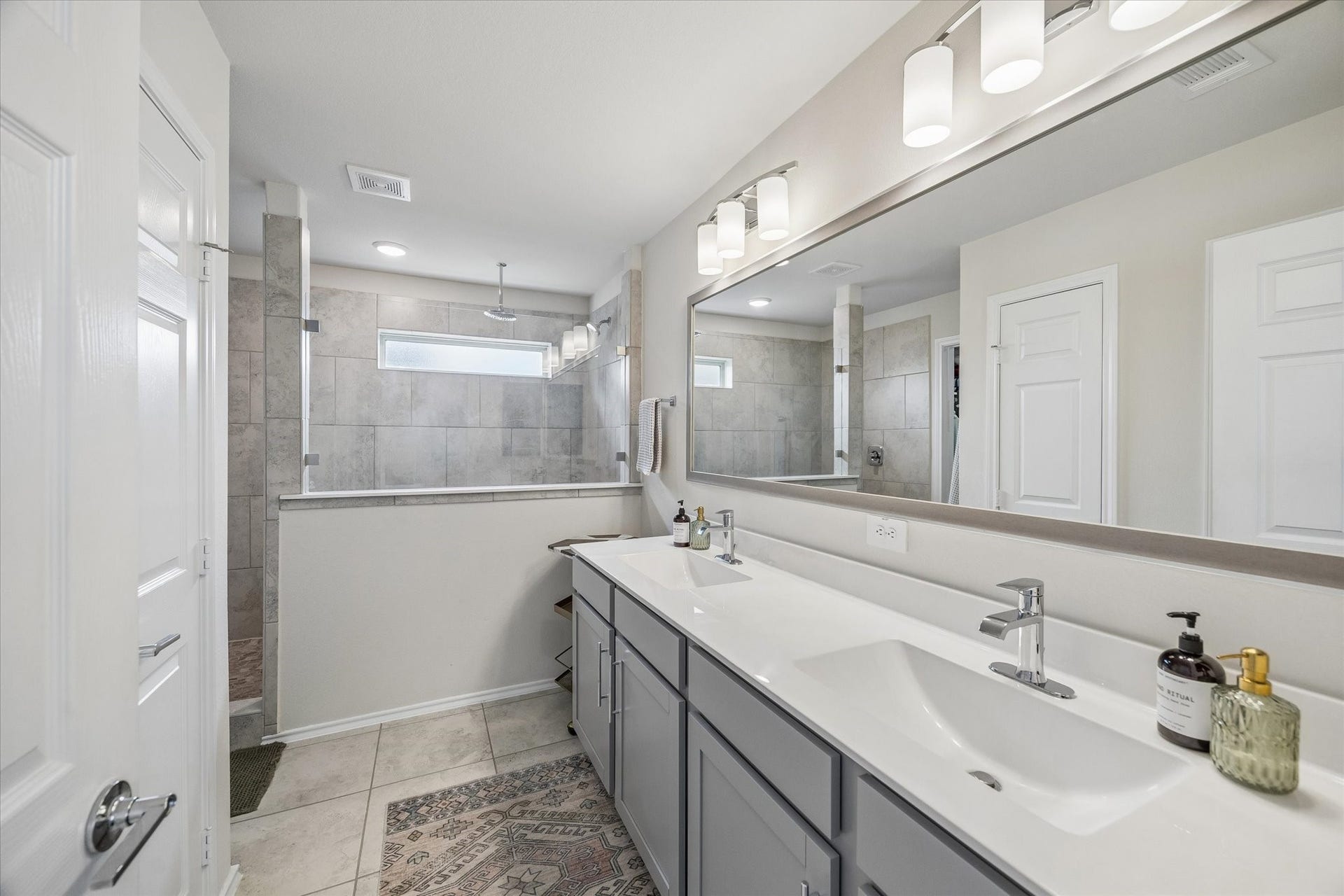Start and end your day in this spacious primary ensuite featuring dual vanities with ample counter space, modern finishes, and an oversized walk-in shower with elegant tile surround.
