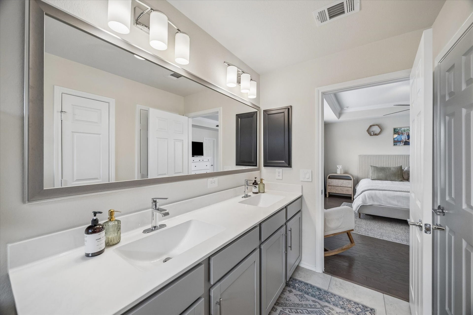 The well-appointed primary bathroom offers a large double-sink vanity, expansive mirror and abundant storage.