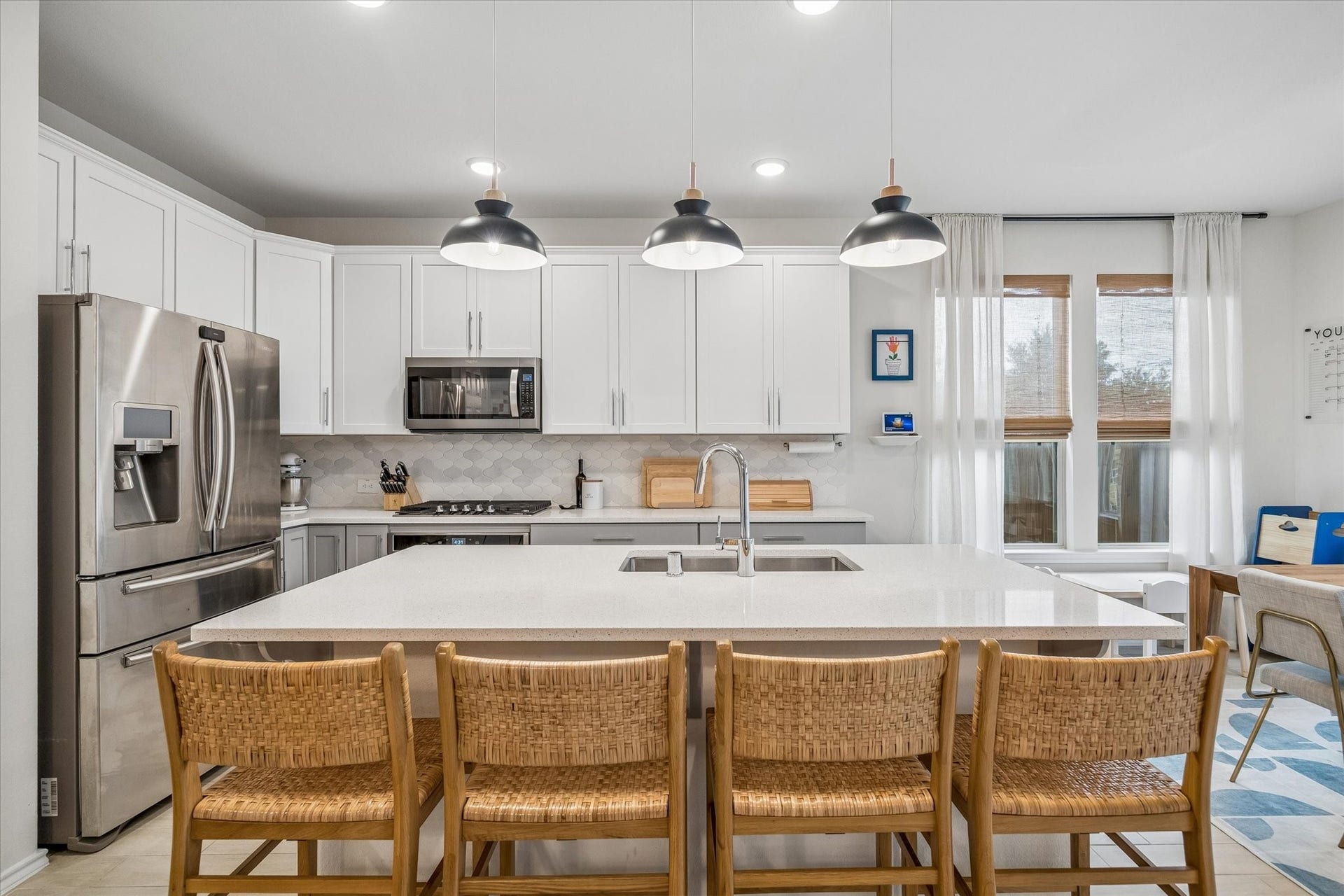 Large center island, quartz countertops, and abundant cabinetry make this kitchen both beautiful and functional.