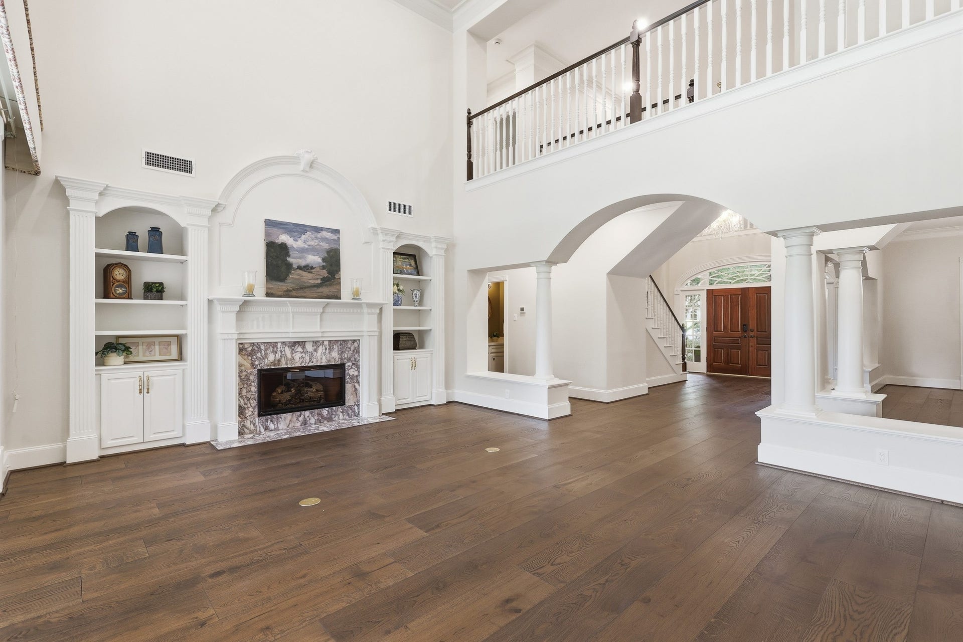 7 Pastoral Pond Circle, The Woodlands, TX 77380 Stunning two-story living room featuring an elegant marble fireplace and custom built-in cabinetry.