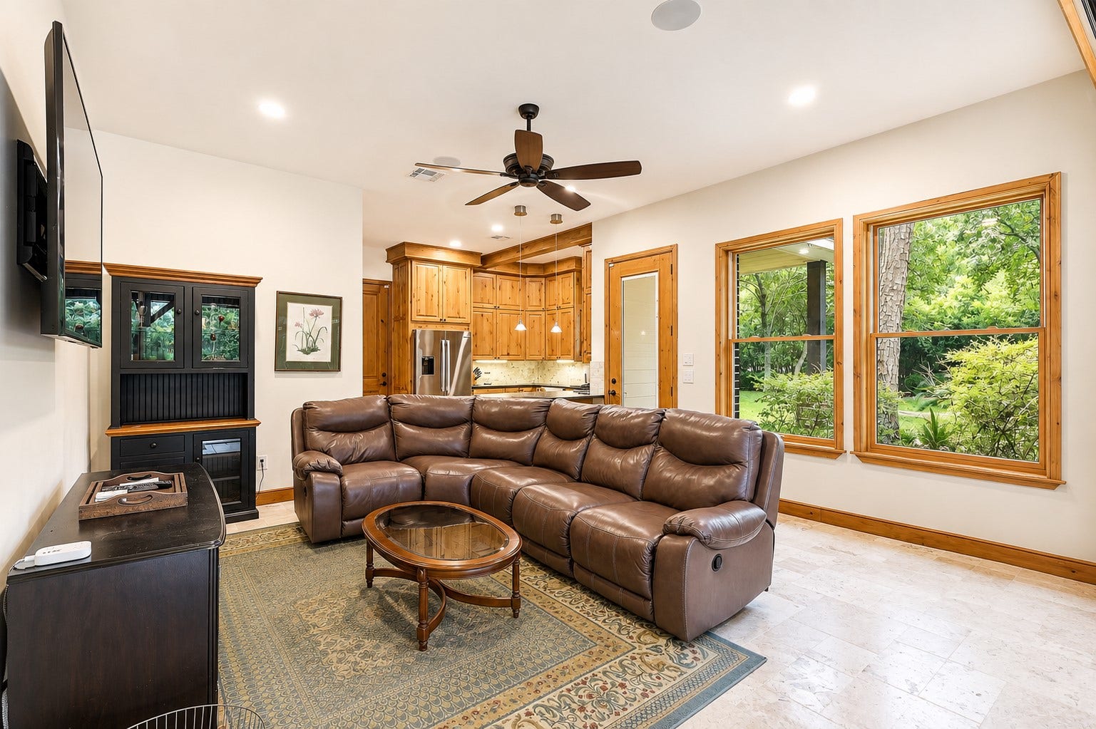 7 Pastoral Pond Circle, The Woodlands, TX 77380 The living room of the guest house features an open-concept layout that flows seamlessly into the outdoor summer kitchen pavilion