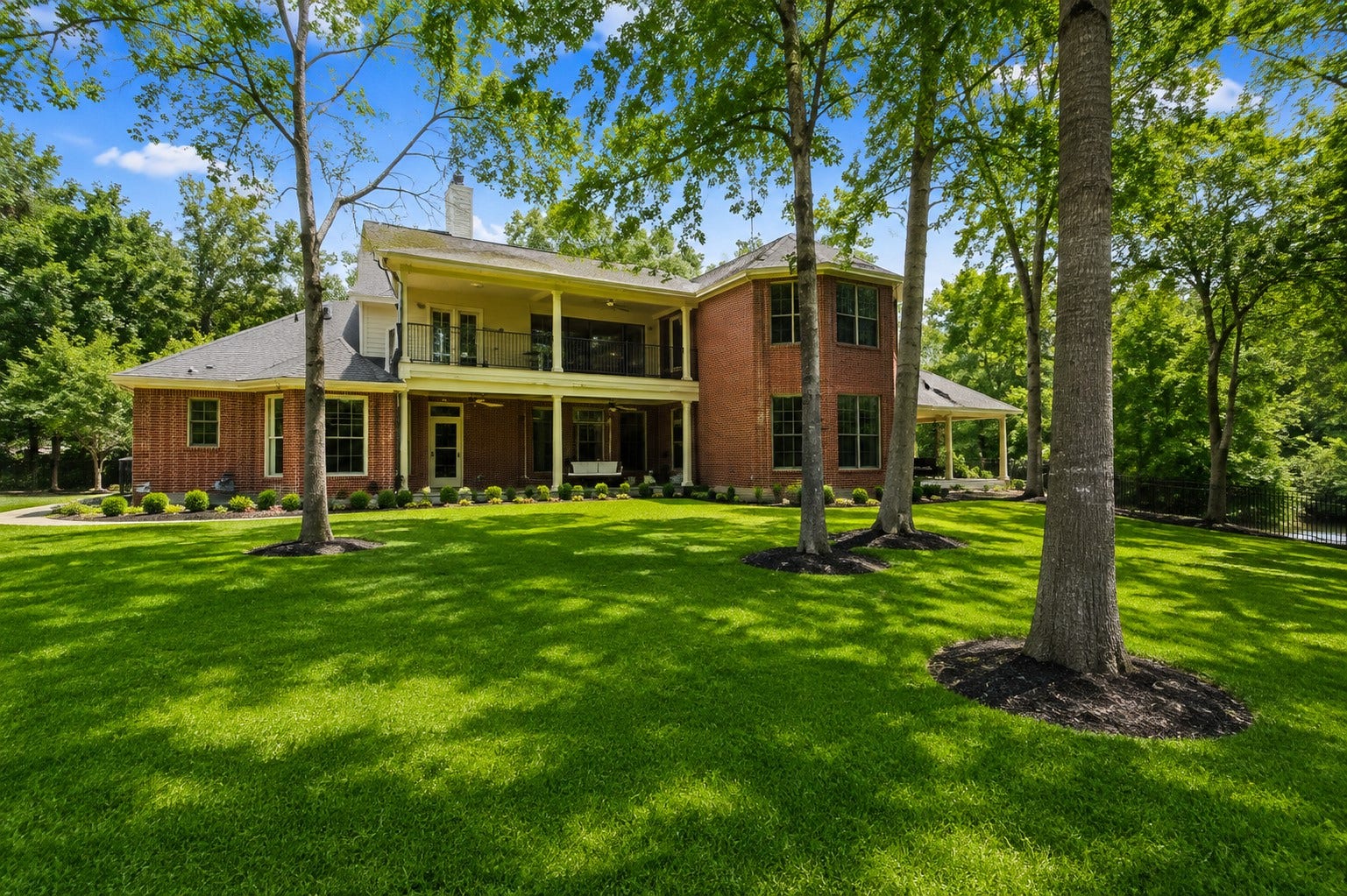 7 Pastoral Pond Circle, The Woodlands, TX 77380 Rear exterior view of the home featuring a lush, manicured lawn.