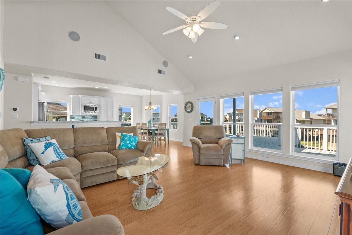 314 Windward Way, Tiki Island, TX 77554 The spacious living room features soaring ceilings, an abundance of natural light, and expansive windows showcasing beautiful waterfront views.