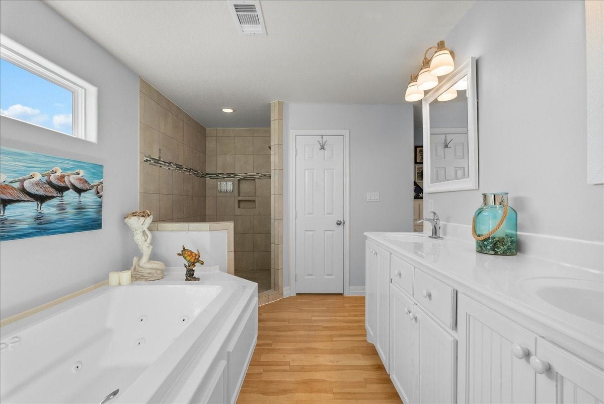 314 Windward Way, Tiki Island, TX 77554 Spa-inspired en-suite with soaking tub, walk-in shower, dual sinks, and walk-in closet.
