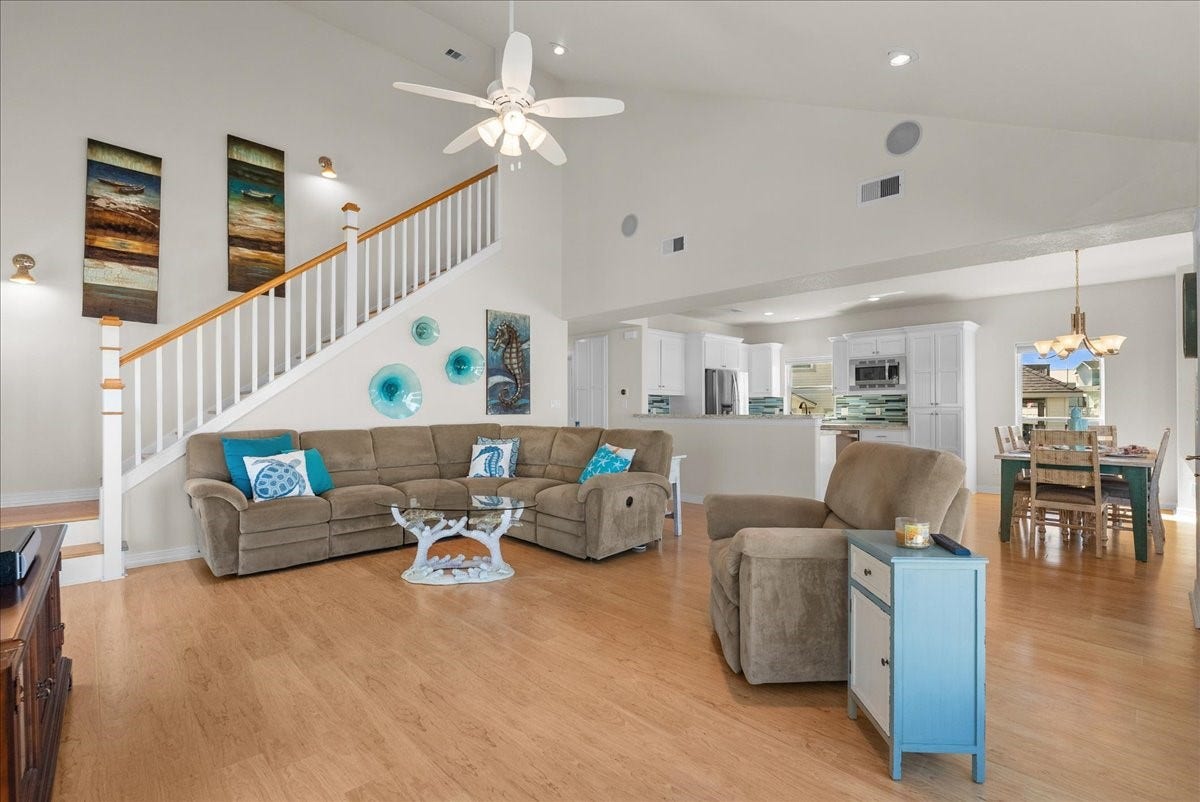 314 Windward Way, Tiki Island, TX 77554 The spacious living room features soaring ceilings, an abundance of natural light, and expansive windows showcasing beautiful waterfront views.
