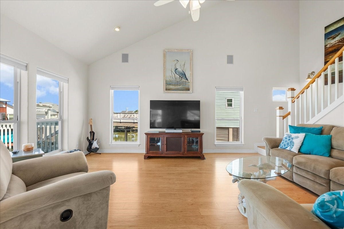 314 Windward Way, Tiki Island, TX 77554 The spacious living room features soaring ceilings, an abundance of natural light, and expansive windows showcasing beautiful waterfront views.