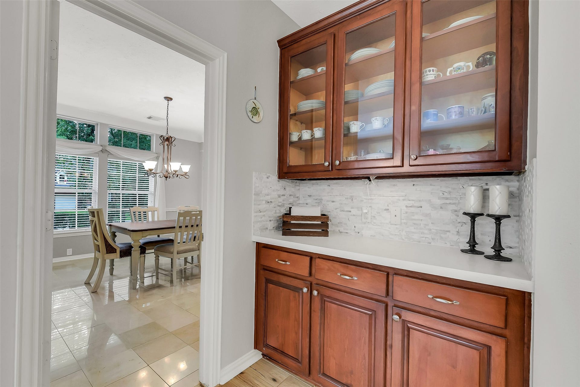 7 Larkspur Trail, The Woodlands, TX 77382 Featuring rich wood cabinetry and glass doors, leading to a bright dining space with large windows and a stylish chandelier.
